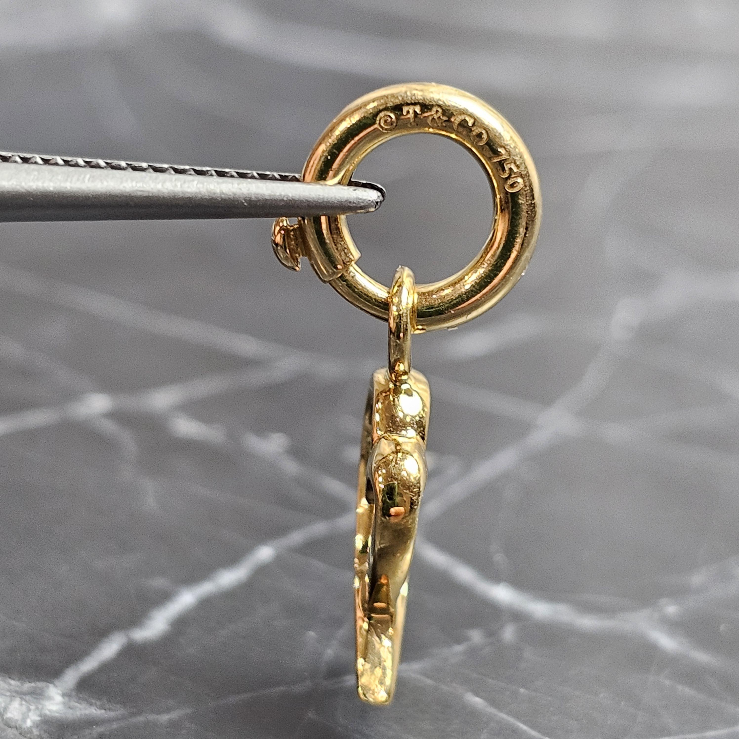 Enhance your collection with this exquisite Tiffany & Co. Paloma Picasso charm. Crafted from 18k yellow gold, this piece features a unique heart-shaped design with a ribbon motif. Its polished finish adds a touch of sophistication, making it a