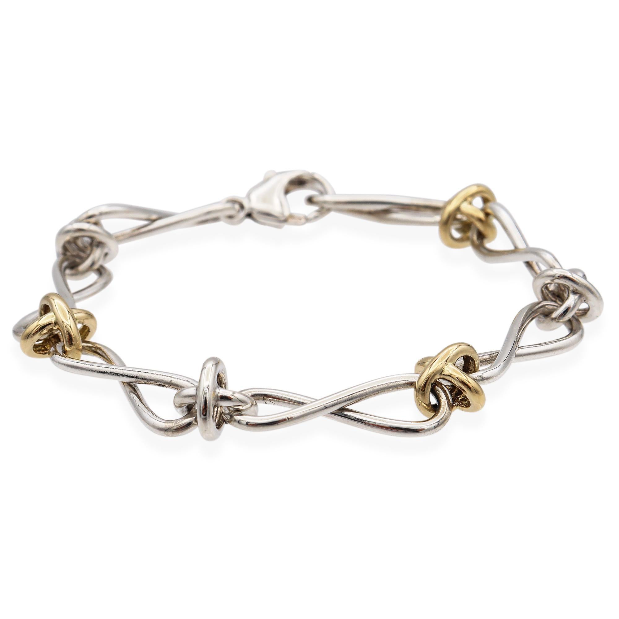 This exquisite link bracelet showcases a harmonious blend of sterling silver and 18k gold. The design features interlocking loops, each crafted with precision, creating a fluid and dynamic form. The silver links are elegantly twisted, while the gold