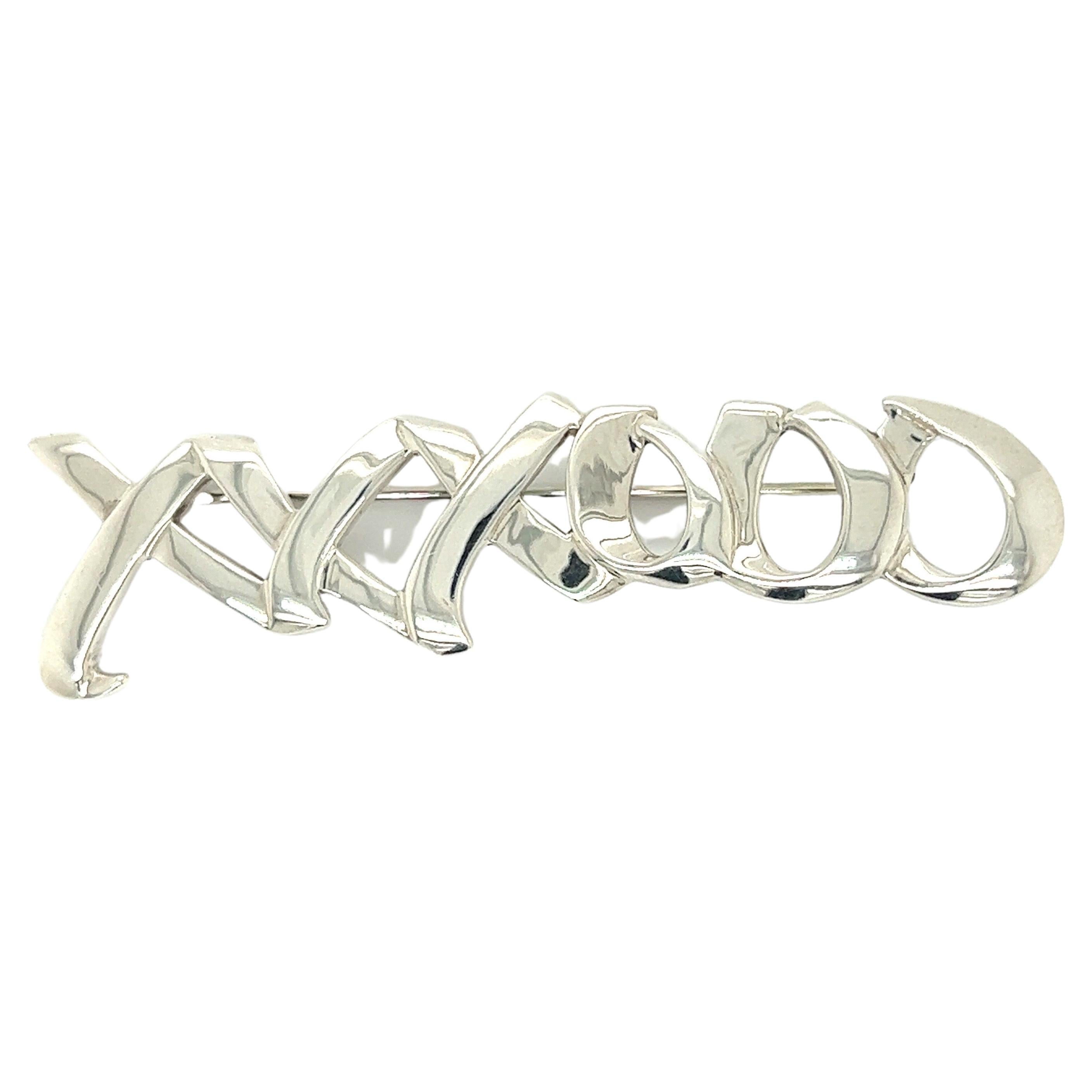 The Iconic silver hugs and kisses brooch by Paloma Picasso for Tiffany & Co. Stamped on the back.  Metal weight is 8.03 grams.  The brooch measures 13 mm x 68 mm.