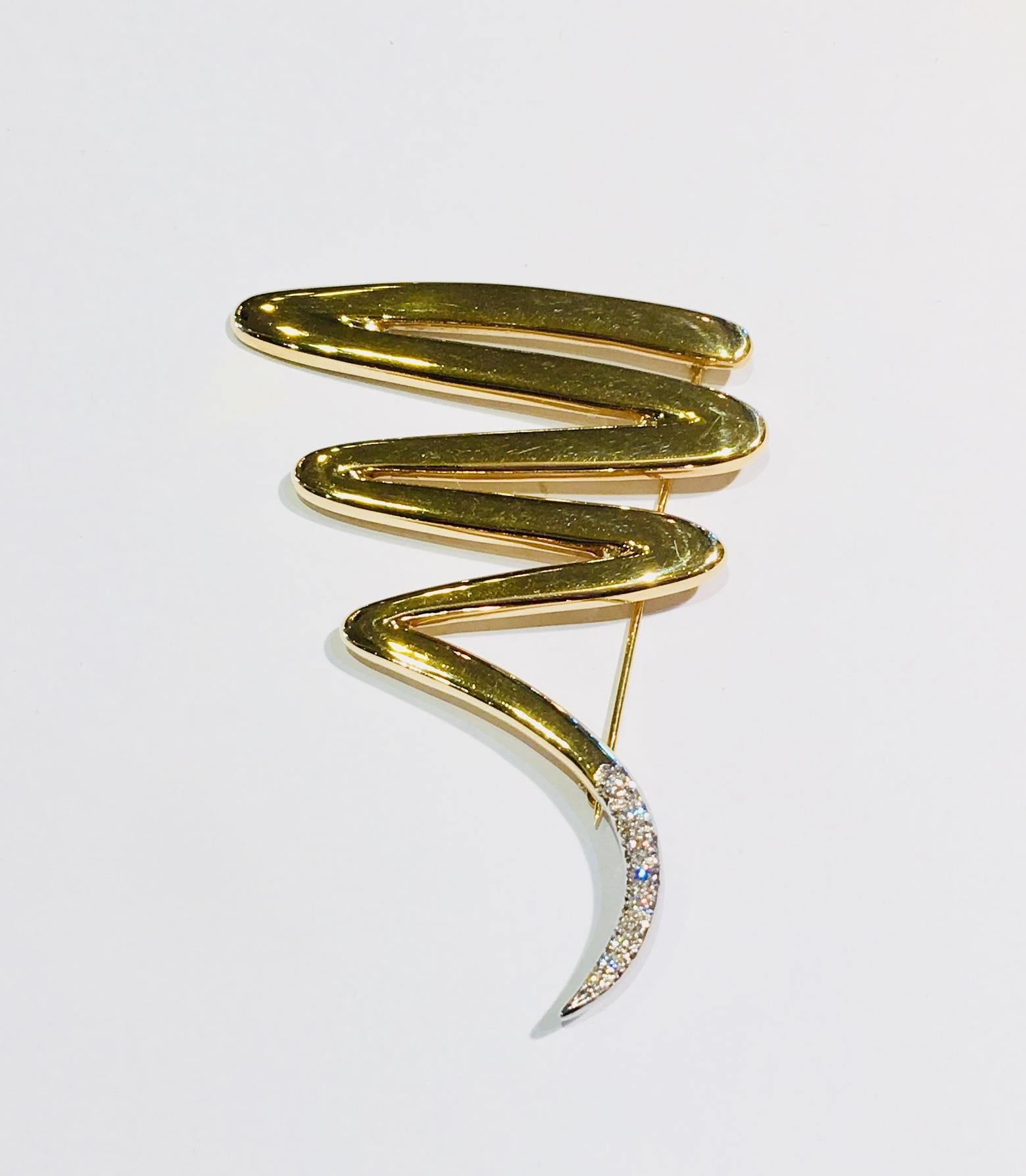 Boldly designed by Paloma Picasso for Tiffany & Co., this estate, two tone 18 karat yellow gold, platinum and diamond brooch pin from 1983 features an abstract zig zag scribble of highly polished 18 karat yellow gold with a platinum and diamond