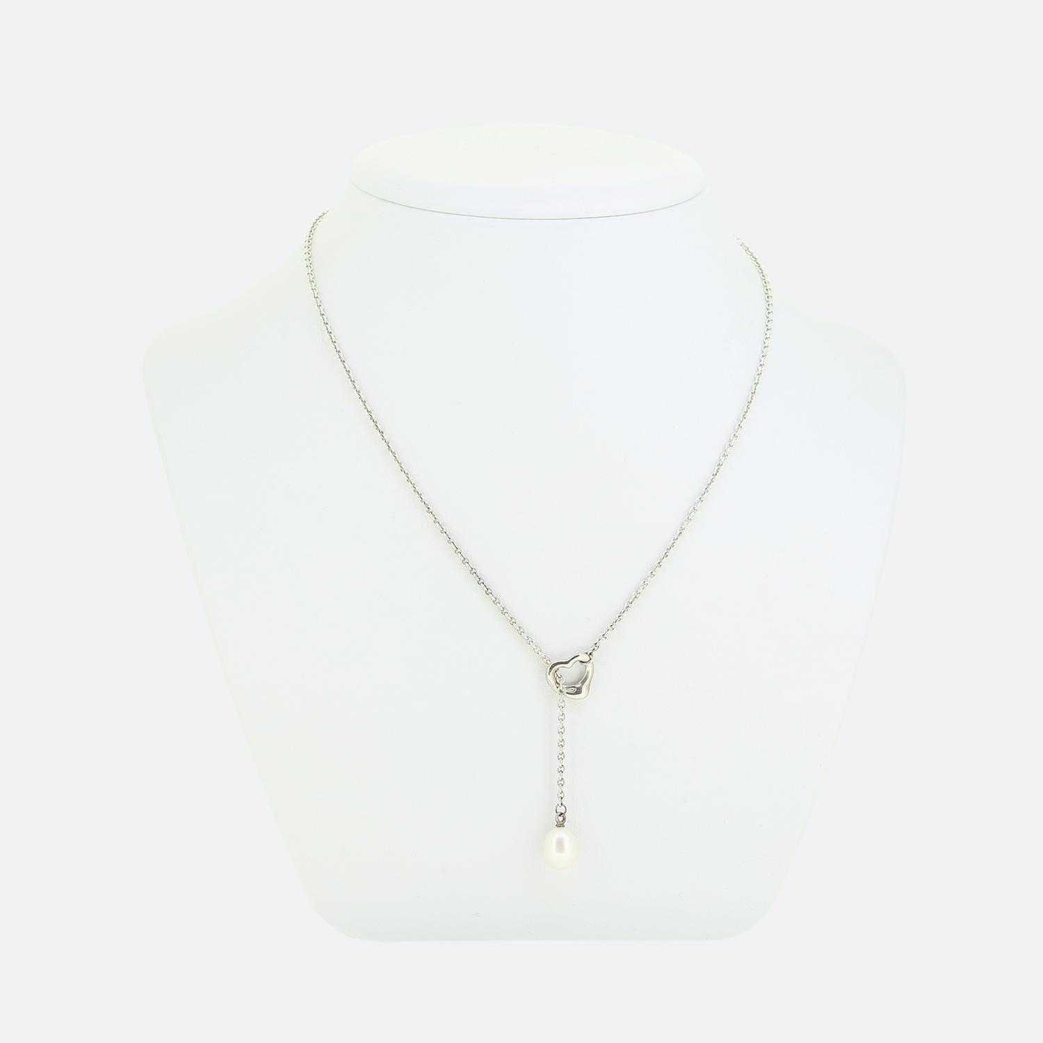 Here we have a charming necklace from Tiffany & Co. This piece forms part of an Elsa Peretti collection and showcases a lariat design consisting of a signed silver belcher chain playing host to a single oval shaped pearl accompanied by an open heart