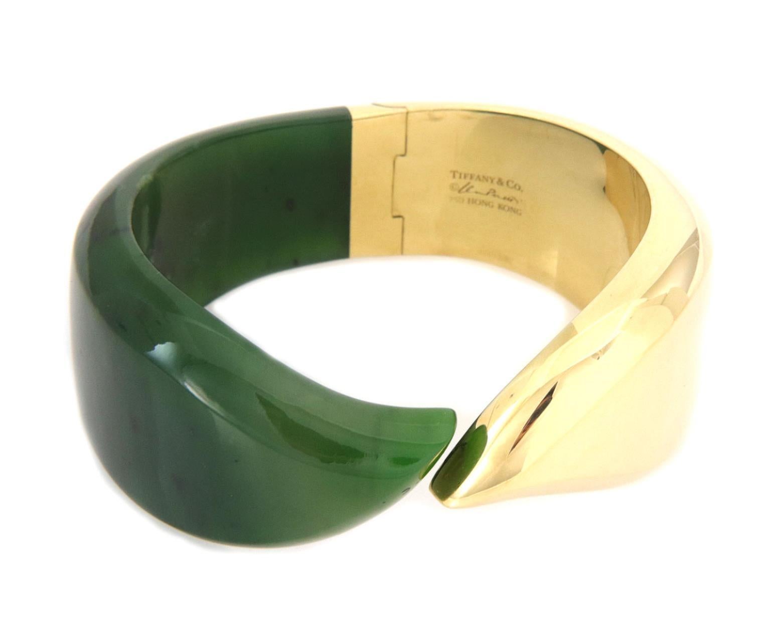 This is a chic authentic and fashionable bracelet from Tiffany & Co. by Elsa Peretti. From 18k yellow gold with a high polished finish featuring a hinge mechanism at the back of the band with half of the band is grass green jade and the other half