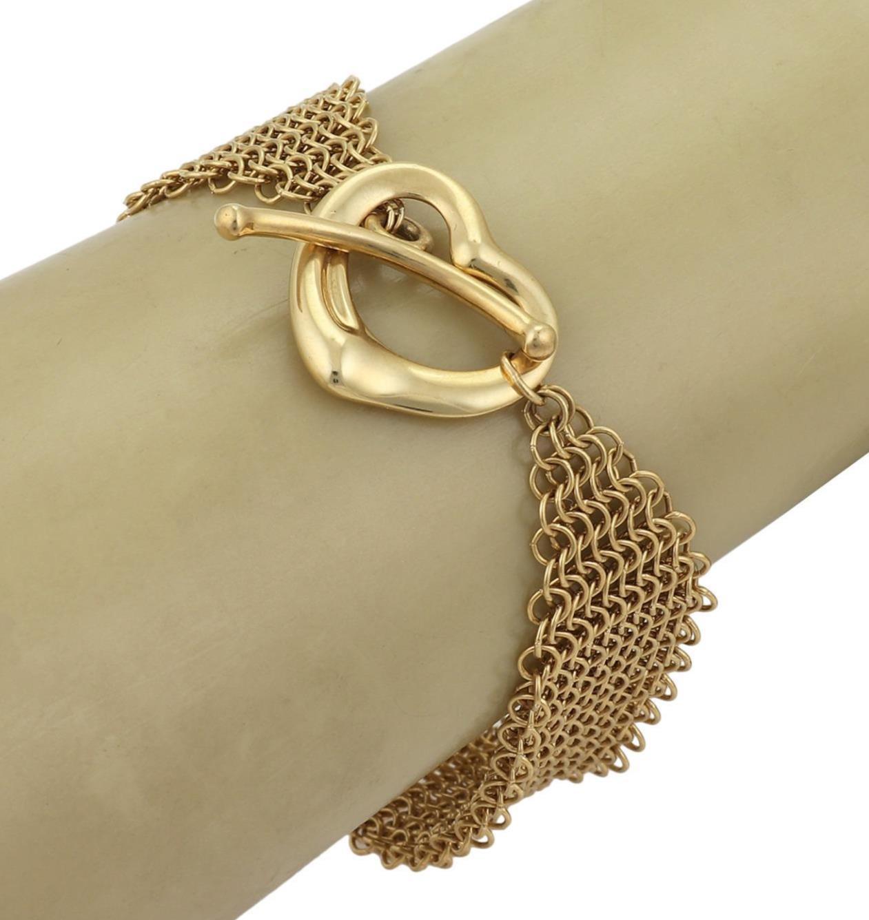 This is a lovely authentic bracelet from Tiffany & Co. by designer Elsa Peretti from her Open Heart collection. It is crafted from 18k yellow gold featuring a 22mm wide mesh link chain bracelet with the Open heart toggle clasp. The mesh chain have a
