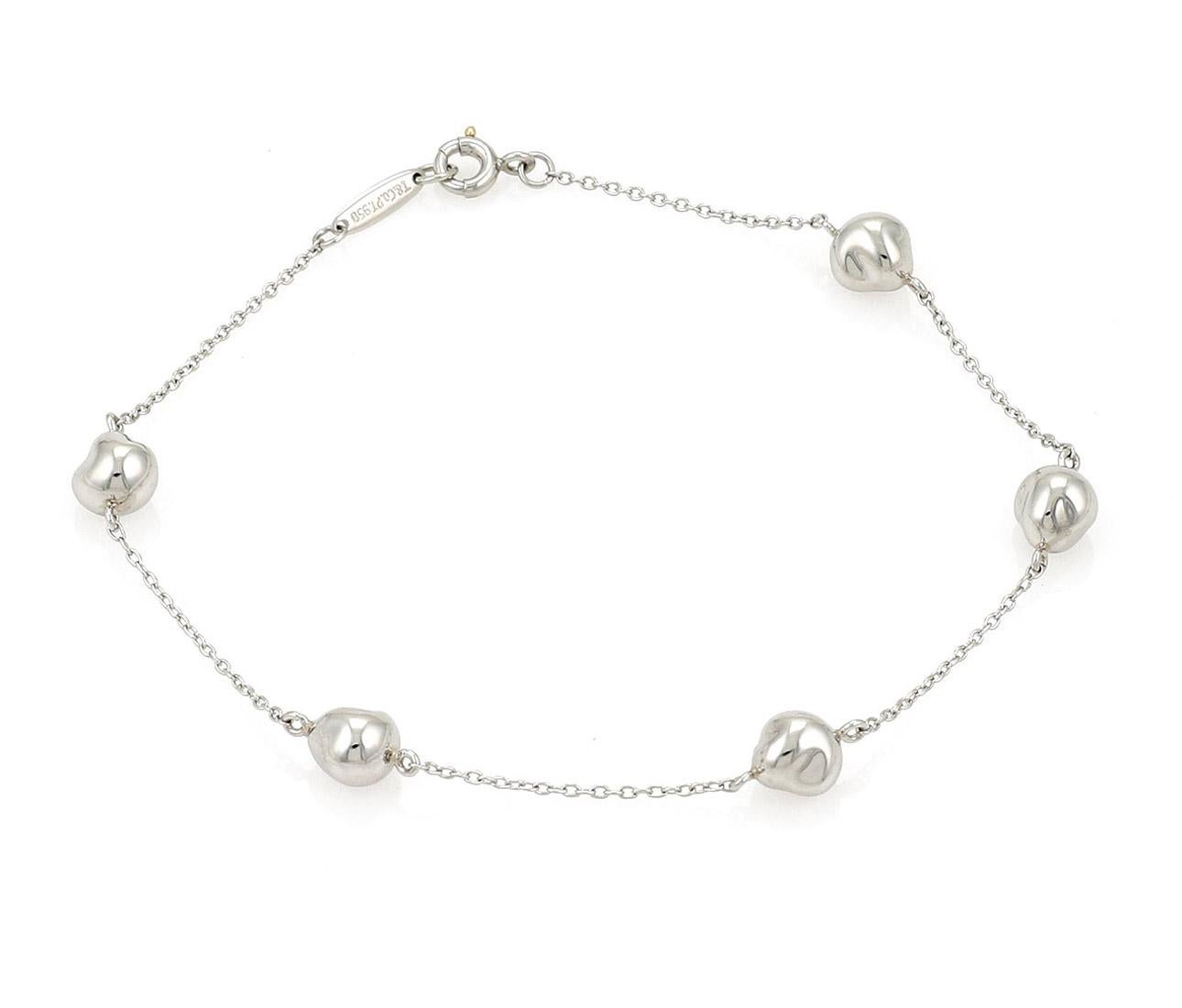 This authentic bracelet is from Tiffany & Co. by designer Elsa Peretti from her Nugget collection. It is crafted from platinum with a high polished finish featuring a chain link bracelet with 5 nugget charms. It fastens with a round clasp and is