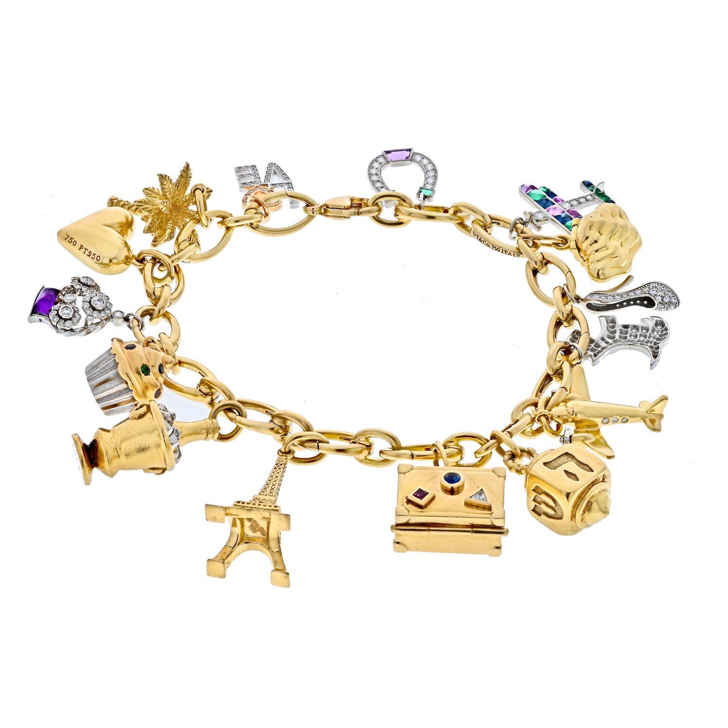 Tiffany & Co. Platin & 18K Gelbgold Gemset und Diamant-Charme-Armband.

An dem goldenen Gliederarmband hängen 15 Charms, darunter eine Palme, ein mit runden Diamanten besetzter Sektkübel, ein Flugzeug, ein mit runden Diamanten besetzter Schuh, ein