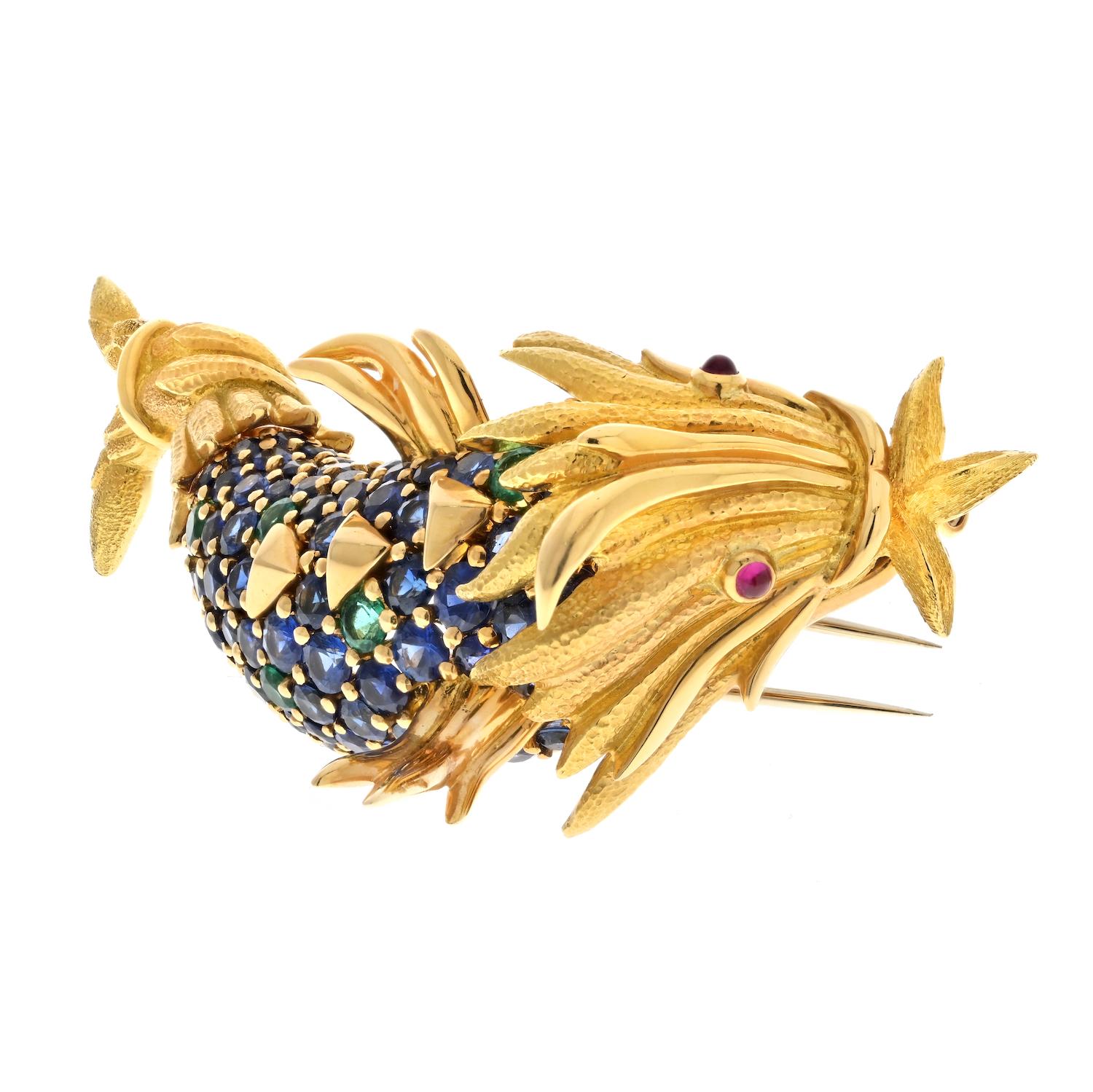 The Tiffany & Co. 18K Gold Schlumberger Sapphire and Green Emerald Koi Fish Brooch is a stunning example of the brand's commitment to fine jewelry craftsmanship. This brooch is made from 18k yellow gold and is mounted with round cut sapphires and