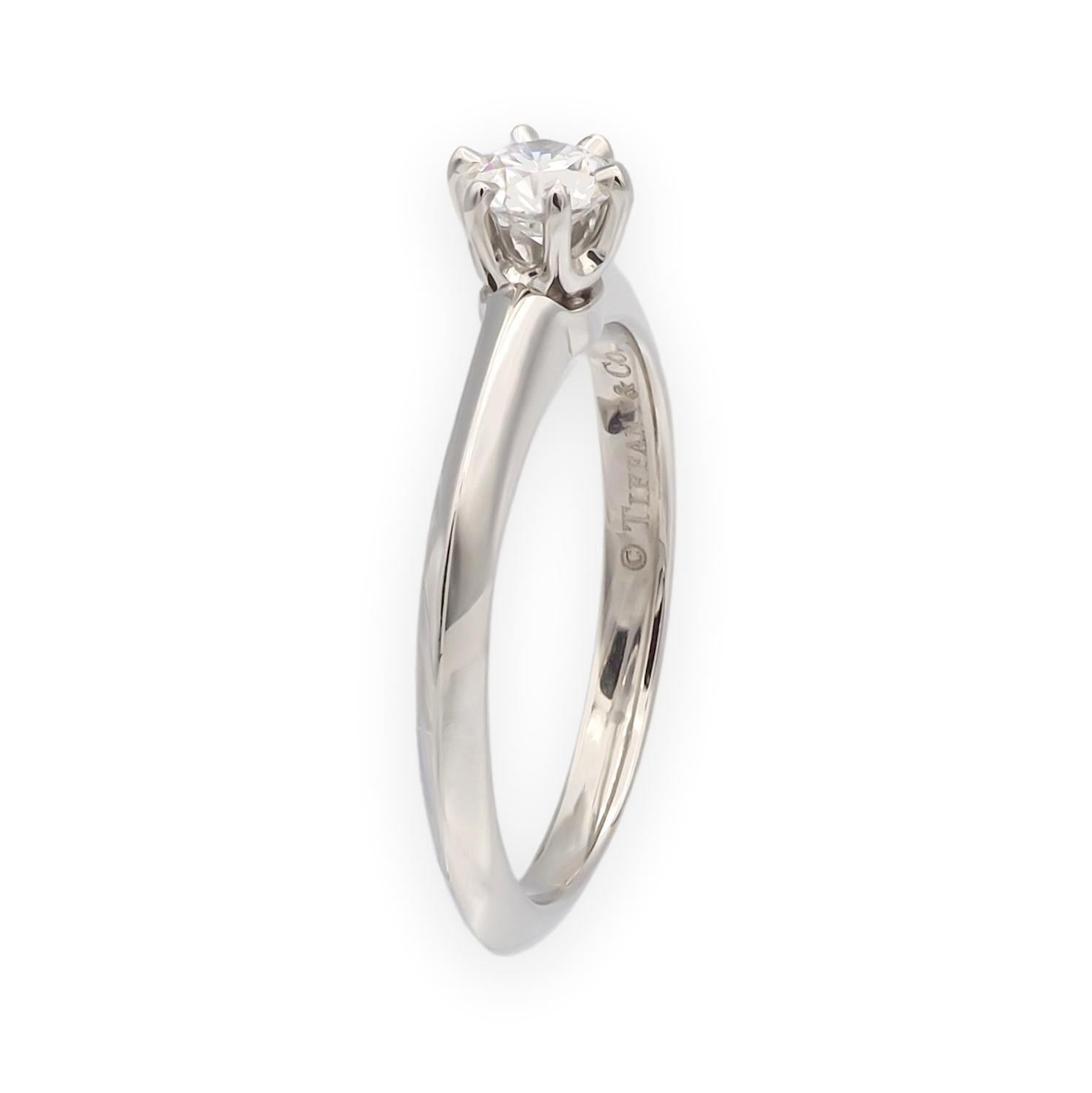 Solitaire classique à six branches de Tiffany & Co. en platine, serti d'un diamant rond de taille brillant de 0,24 carat de couleur D et de pureté VVS2. La bague présente l'anneau traditionnel de Tiffany et un poinçonnage correspondant au certificat