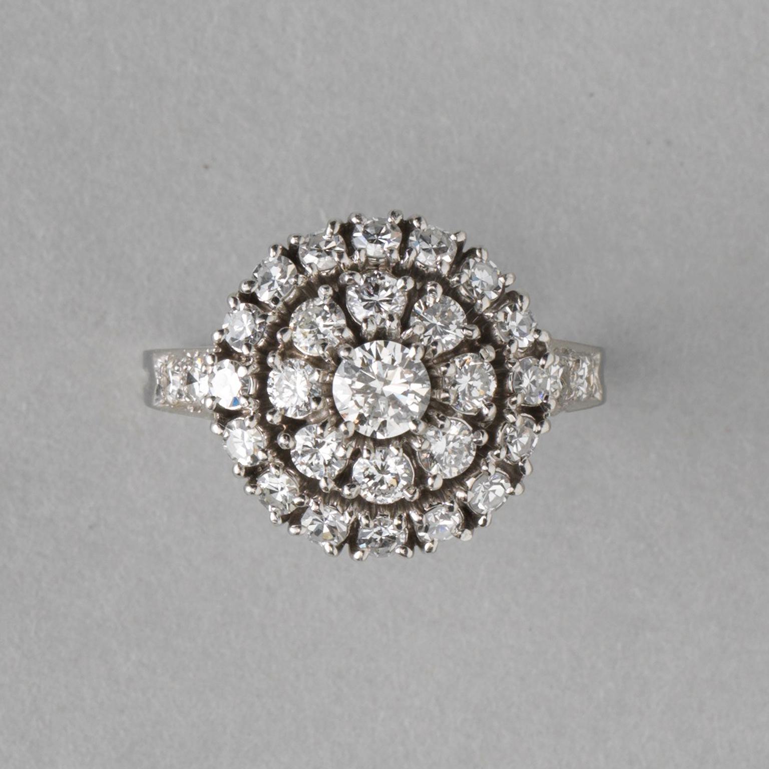 A platinum and iridium cluster ring set with brilliant cut diamonds, around a center stone (app. 0.25 carat), is a row of 8 diamonds (each app. 0.075 carat), the outer border consists of 16 diamonds  (each app. 0.05 carat) and in the shank are two