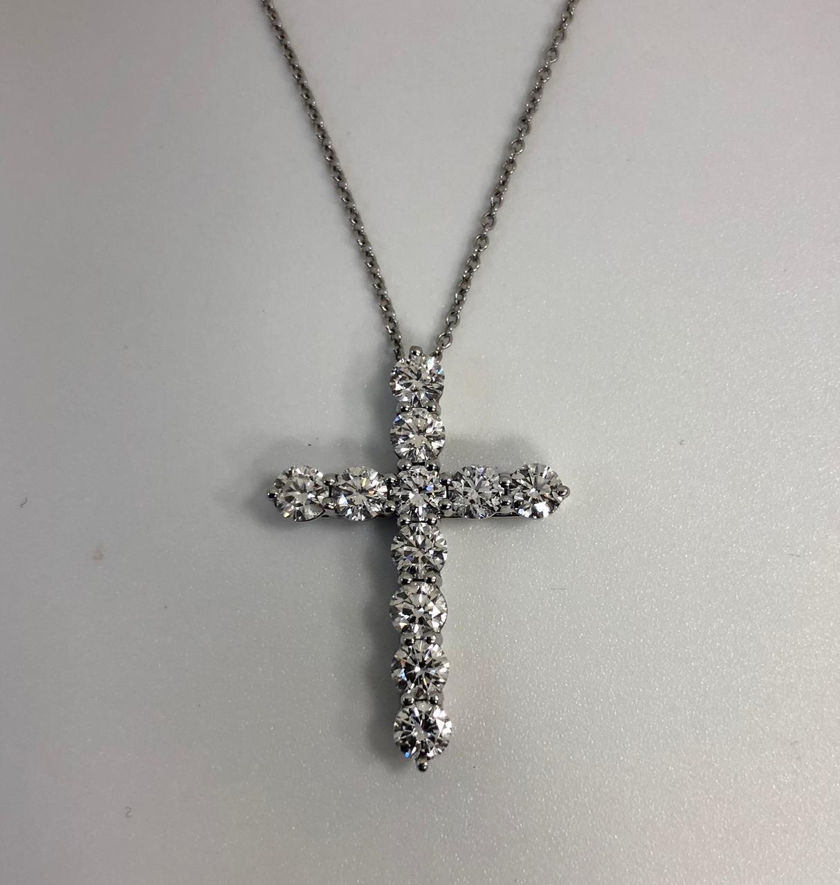 The diamond cross, cruciform pendant, by Tiffany & Co. is crafted in platinum, large size, and suspended from a 16 inch cable link platinum chain. It is shared prong set with 11 Round Brilliant Cut diamonds totaling approximately 2.07 carats, F-G