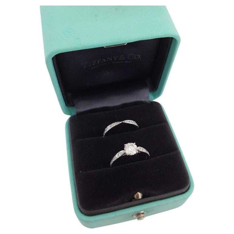 Tiffany & Co. Platinum Channel-Set Diamond Engagement Ring and Band Set is an exquisite pairing. Both rings together weigh 5.5 grams and are sized 5.75. The centerpiece is a natural 0.82 ct Round Brilliant Cut diamond, graded E in color and VS1 in