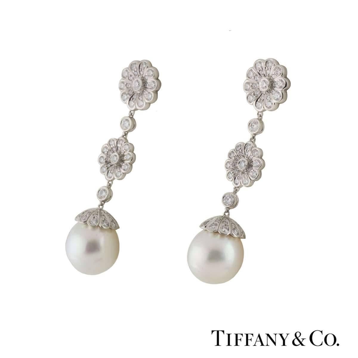 A beautiful pair of platinum diamond and pearl Tiffany & Co. drop earrings. The earrings comprise of flower motifs dangling freely with round brilliant cut diamonds in a pave setting. Complementing the motifs are pearls 10mm in diameter. The