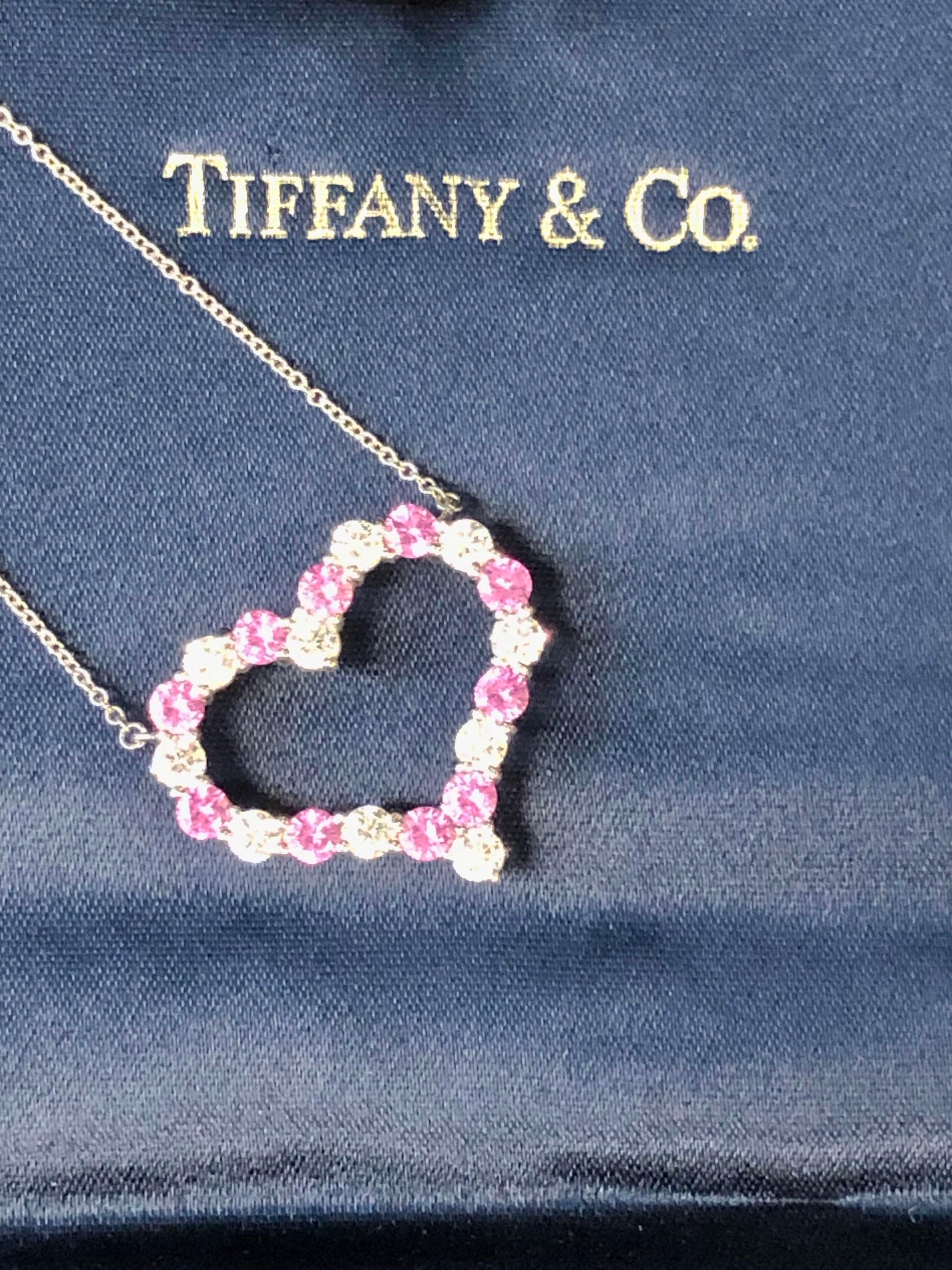 Circa: 2018 Tiffany & Company Platinum Open Heart Pendant Necklace, the Heart measures 1 X 7/8 inch and is set with Round Brilliant cut Diamonds totaling 1 Carat and grading as G in color and VS clarity, further set with Round Pink Sapphires of very