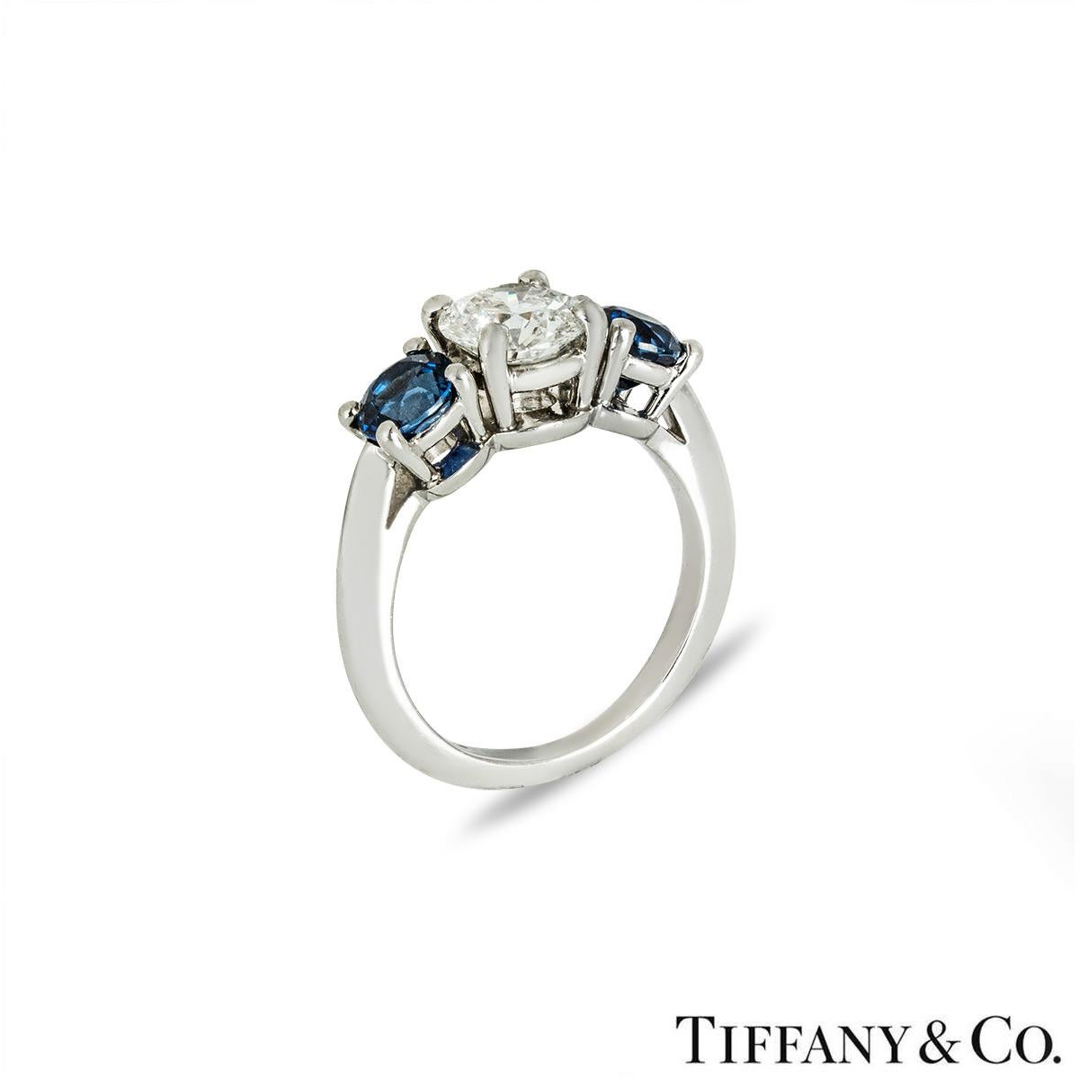 Ein atemberaubender Platinring mit Diamanten und Saphiren von Tiffany & Co. Der Ring besteht aus einem runden Diamanten mit Brillantschliff in der Mitte und einem Saphir auf jeder Seite in einer Fassung mit vier Krallen. Der runde Diamant im