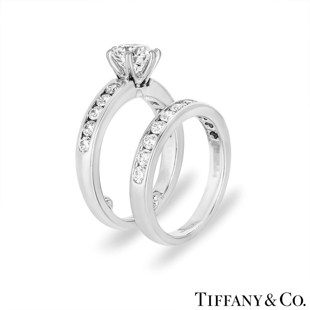 A beautiful platinum diamond bridal set by Tiffany & Co. The engagement ring is set to the centre in a six-prong mount with a round brilliant cut diamond weighing 1.03ct, H colour and VS1 clarity. The centre diamond is further complemented with 10