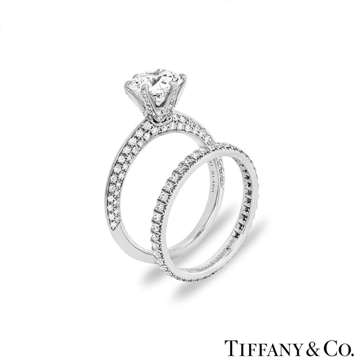 A breathtaking platinum diamond bridal set by Tiffany & Co. The engagement ring is set to the centre in a six prong mount with a round brilliant cut diamond weighing 1.60ct, F colour and VVS2 clarity. The diamond scores an excellent rating in all