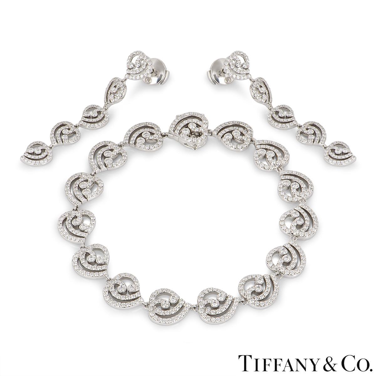A scintillating platinum diamond jewellery suite from Tiffany & Co. The earrings and bracelet feature a swirl design pave set with round brilliant cut diamonds with a combined approximate weight of 3.35ct. The earrings measure 1.75 inches long and