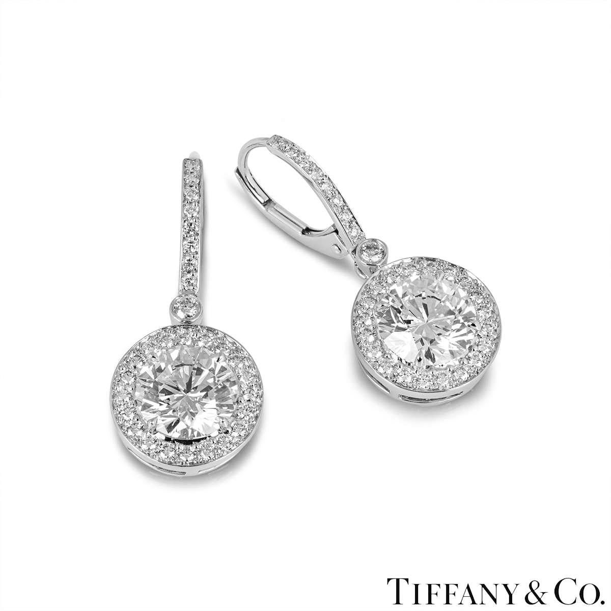 A magnificent pair of platinum diamond earrings by Tiffany & Co. Each earring is set with a round brilliant cut diamond, complemented by a halo of pave set diamonds and a diamond set drop. The first diamond weighs 1.51ct, G colour and VS2 clarity.