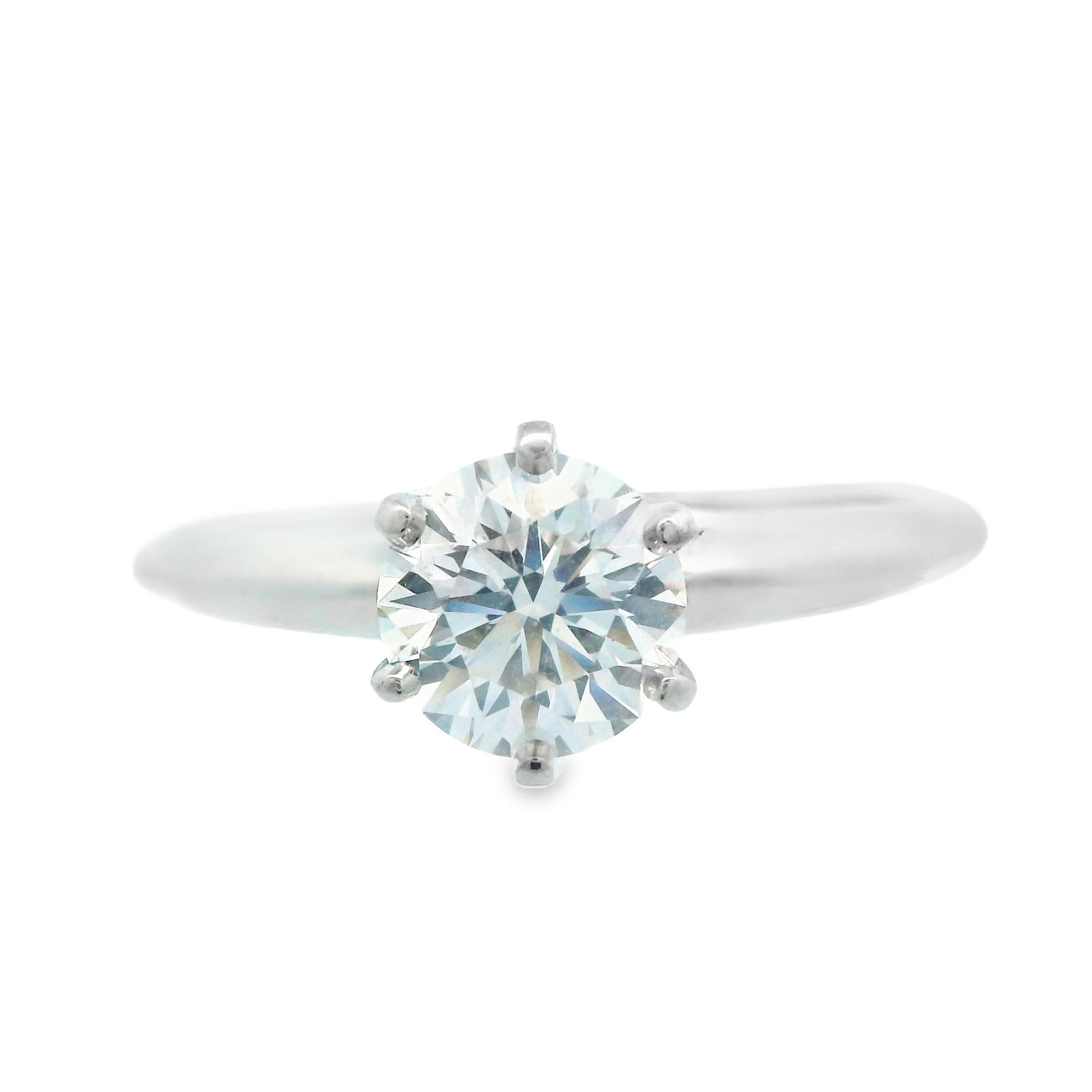 This gorgeous engagement ring is a classical 6 prong diamond engagement ring from Tiffany & Co.The ring is a solitaire style ring with a solid white platinum band, marked Tiffany & Co. on the inside. The ring features a bright white, 1.03 carat, G