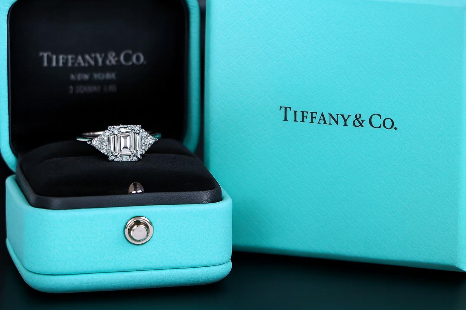Tiffany & Co. Platinum Emerald Cut and Trillion Diamond Engagement Ring

This classic Tiffany & Co. engagement ring features a stunning emerald cut diamond weighing 1.28 carats, graded D color and VVS2 clarity. The diamond is laser-inscribed T&Co.
