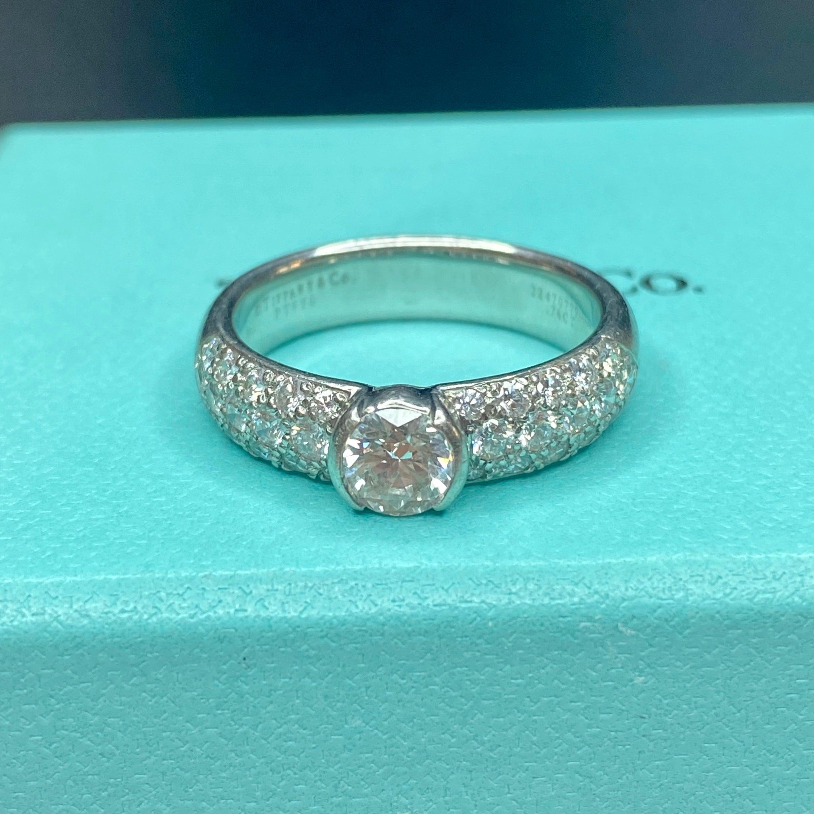 Tiffany & Co. platinum engagement ring from the Etoile collection, featuring a round brilliant cut diamond solitaire with pave' diamond set shoulders. Original diamond certificate included. 
Center diamond: 0.76ct. Color: H, Clarity: VS1
30 round
