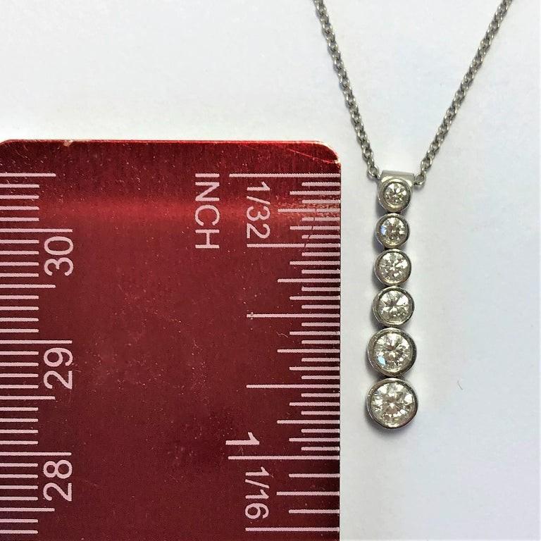 Made of platinum and signed Tiffany & Co and PT950, this modern yet classic design pendant is bezel set with six round brilliant cut diamonds weighing a total of .45CT of overall F Color and VS1 Clarity. The pendant measures 7/8 inches long and the