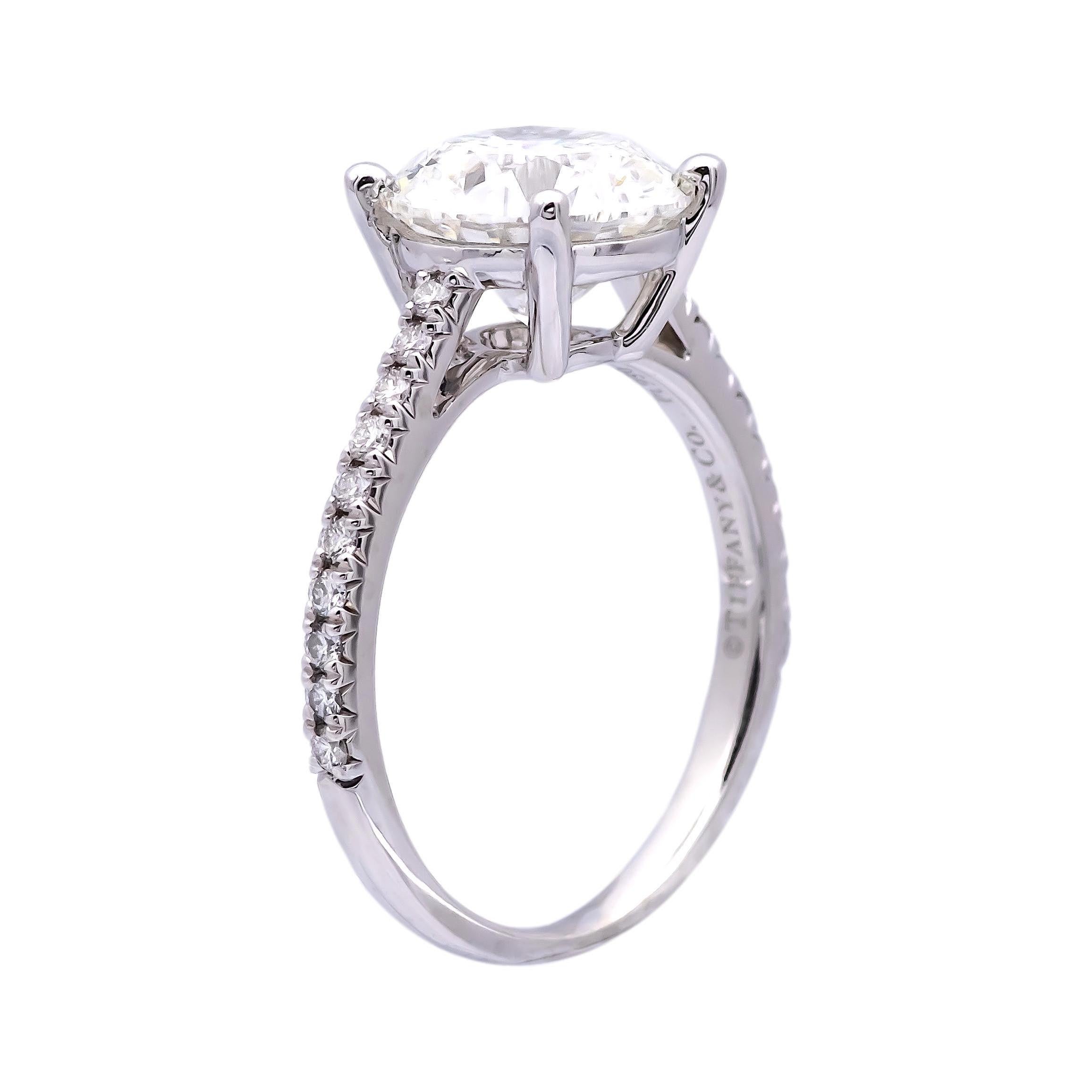 Tiffany & Co. engagement ring from the Novo collection finely crafted in platinum featuring a round brilliant cut diamond center weighing 2.39 carats , G color , VS2 clarity set in a 4 prong basket setting with airline and adorned with 16 bead set