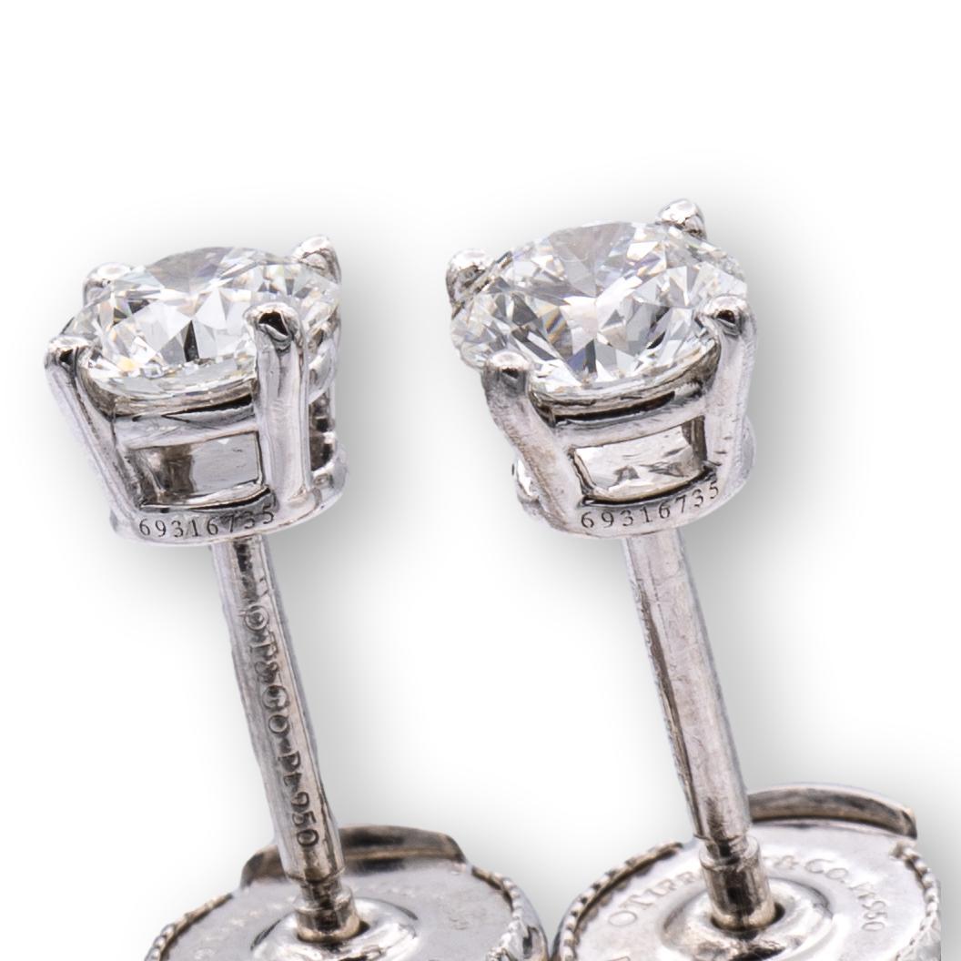 Pair of Tiffany & Co. Diamond Stud earrings finely crafted in a Platinum 4 prong basket setting featuring two perfectly matched round brilliant cut diamonds weighing 0.90 carats total weight. One round brilliant diamond weighs 0.45 carats graded G