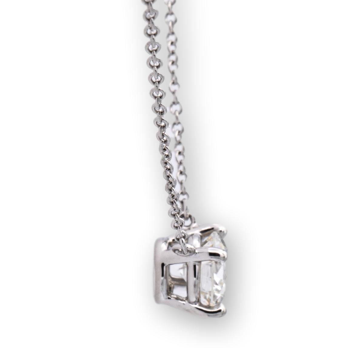 Tiffany & Co. Diamond Solitaire pendant finely crafted in platinum with a round brilliant cut diamond center weighing 1.04 carats J color VVS2 clarity. The diamond is set in a 4 prong basket setting hanging off a 16