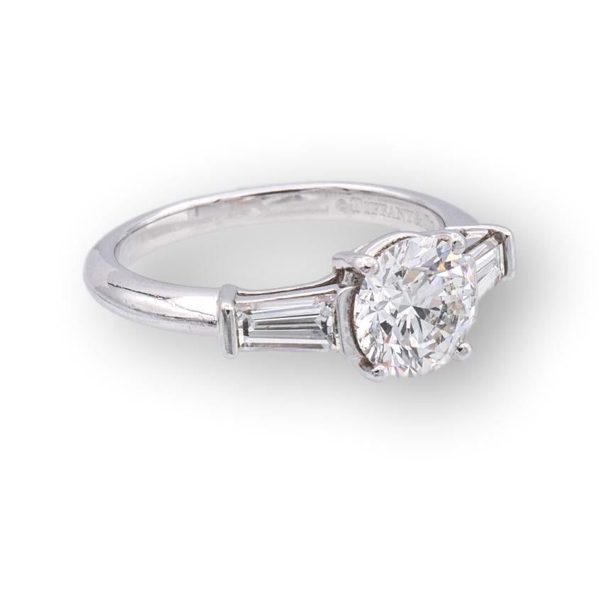 Tiffany & Co. Vintage diamond engagement ring finely crafted in platinum with a round brilliant cut center weighing 1.26 carats I color VS1 clarity flanked by 2 tapered baguette diamond sides weighing 0.59 carats total weight D-G color IF-VS clarity