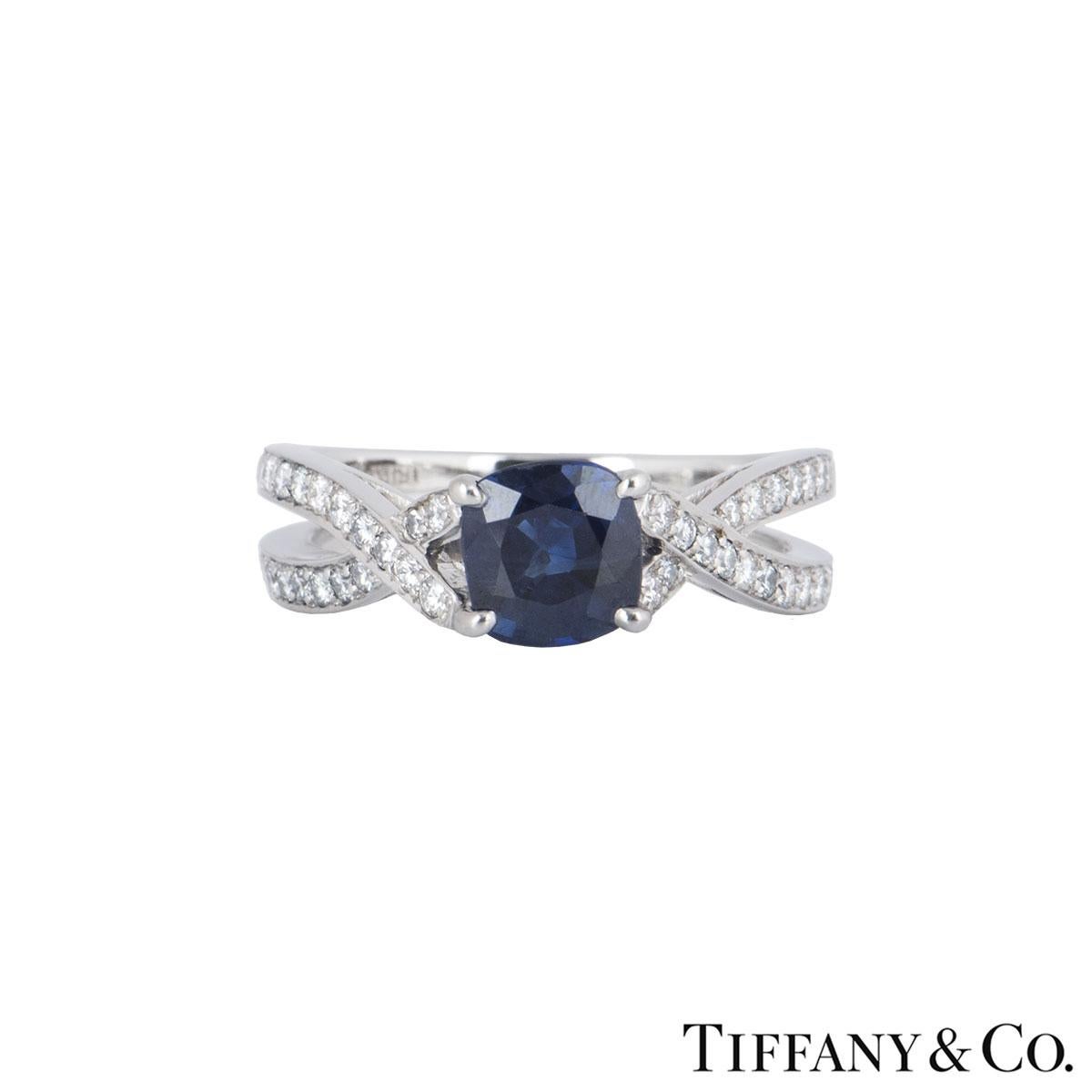 An impressive sapphire and diamond dress ring in platinum by Tiffany & Co. The ring comprises of a cushion shape sapphire with an approximate weight of 0.90ct. Surrounding the central stone are 38 round brilliant cut diamonds half set on the band in