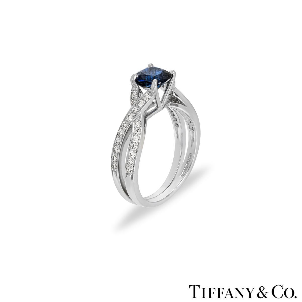 An elegant platinum sapphire and diamond dress ring by Tiffany & Co. The ring features a cushion shaped sapphire with an approximate weight of 0.90ct, displaying a deep blue hue. Complementing the sapphire are 38 round brilliant cut diamonds pave