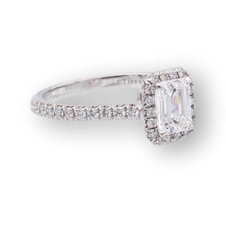 Tiffany & Co. engagement ring from the Soleste collection finely crafted in platinum featuring an emerald cut diamond center weighing 0.71 carats F color , fine VVS2 clarity adorned with a halo of 18 round brilliant cut bead set diamonds and 20 bead