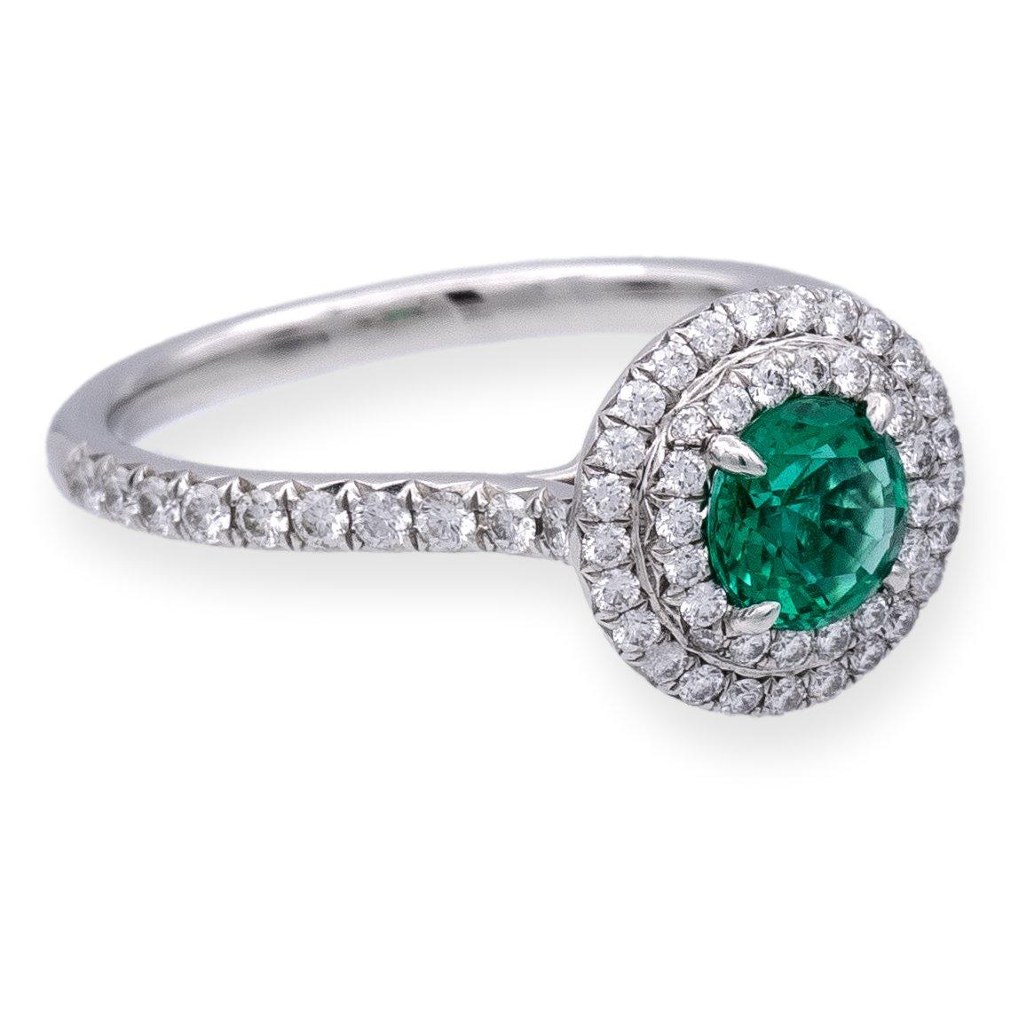 Tiffany & Co. Emerald Soleste Ring, a true gem from the revered Soleste collection. This platinum masterpiece showcases a vibrant .45 carat green emerald, elegantly encircled by a double halo of meticulously bead-set diamonds. The play of light is