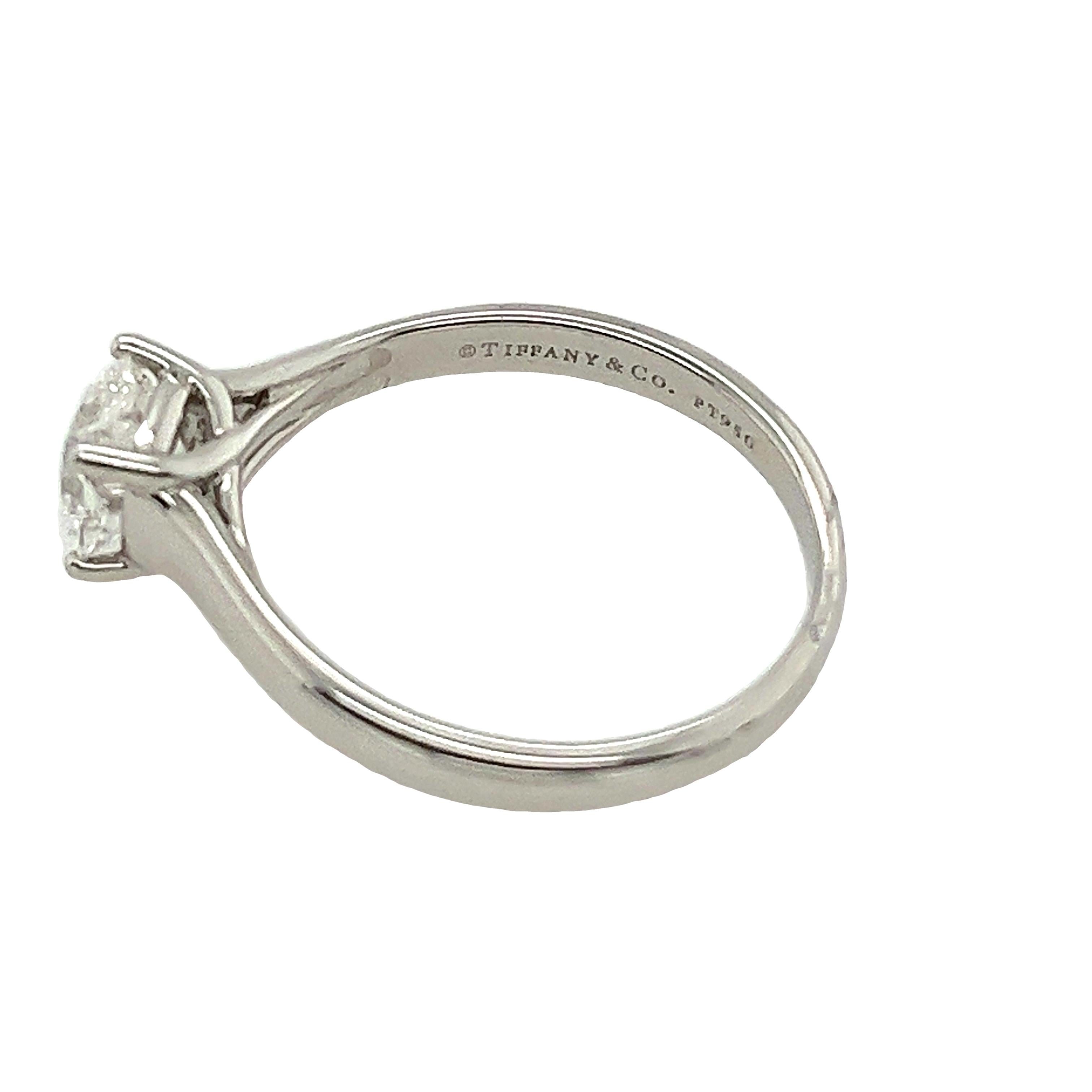 Behold the pinnacle of elegance: the Tiffany & Co. Platinum Solitaire Ring. Adorned with a magnificent 0.87-carat F/VS2 Lucida cut cornered square diamond, this masterpiece exudes timeless sophistication. Set in platinum, its classic design