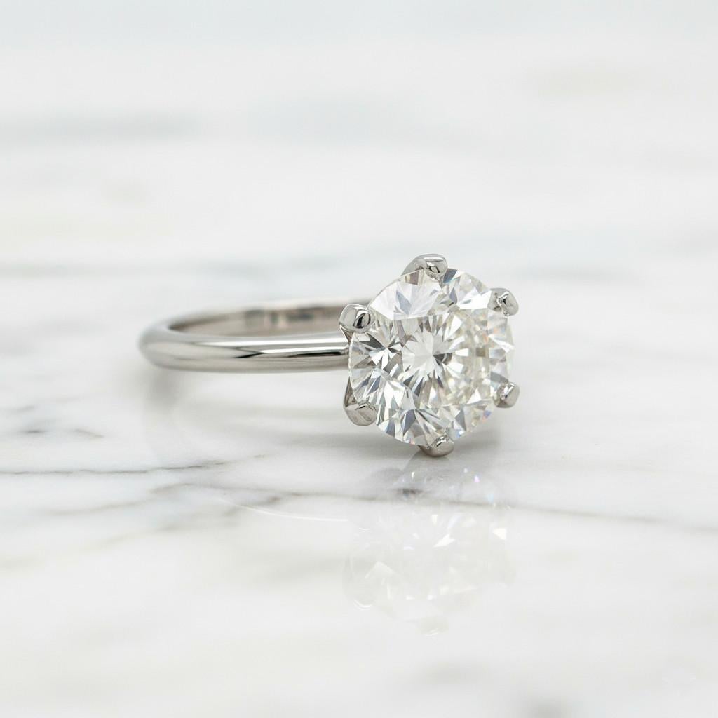 Cette bague solitaire raffinée de Tiffany & Co. incarne l'élégance intemporelle et le savoir-faire qui distinguent la Maison depuis des générations. Le diamant central, d'environ 3 carats, présente une magnifique taille ronde brillante, d'une