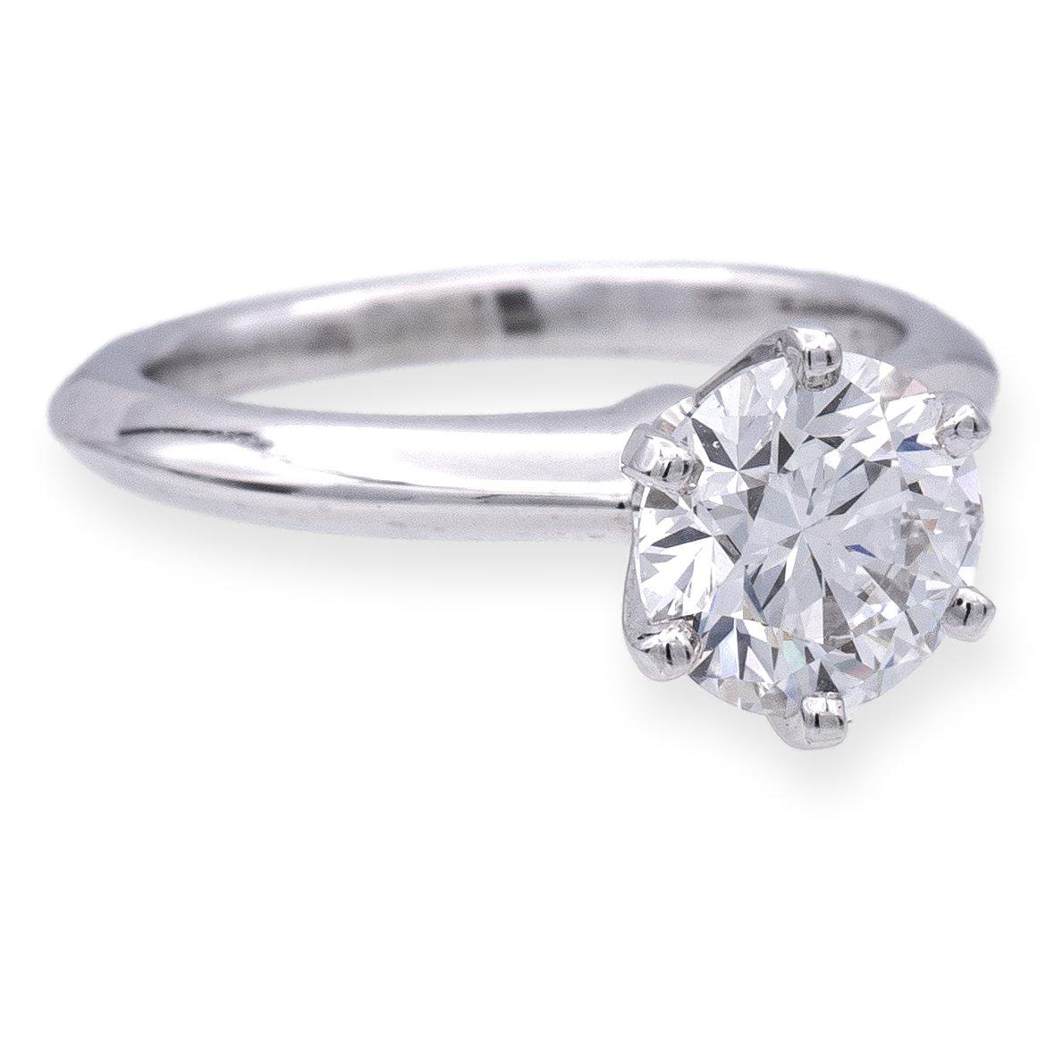 Tiffany & Co. Classic Diamond Engagement Ring crafted with precision in a six-prong platinum setting, it showcases a brilliant 1.21 carat round diamond at its core. Graded F color and VS1 clarity, the diamond's beauty is enhanced by its Excellent