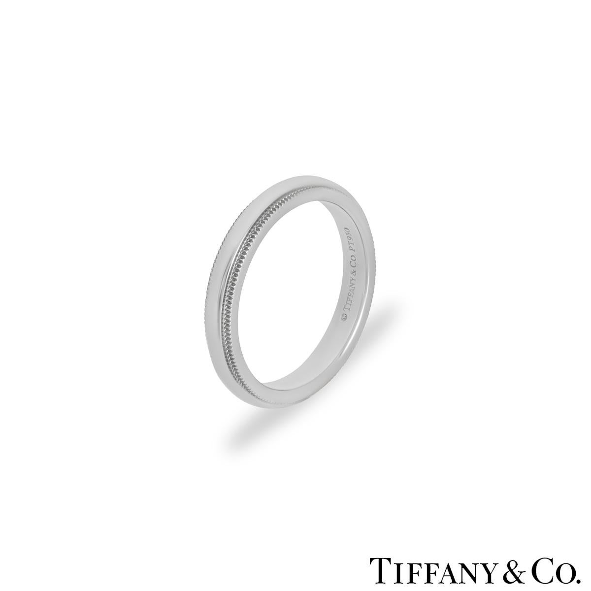 A modern platinum wedding band by Tiffany & Co. from the Tiffany Together collection. The ring features a high polish centre with textured milgrain edges. It measures 3mm in width, is a size UK L½ - EU 51½  and has a gross weight of 5.71