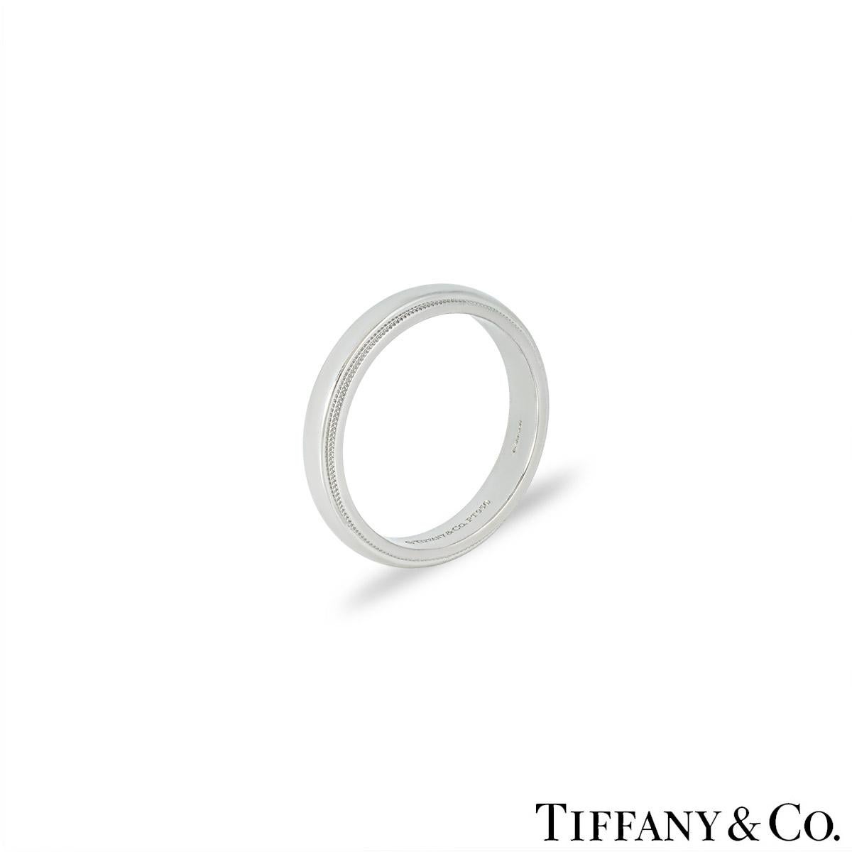 A modern platinum wedding band by Tiffany & Co. from the Tiffany Together collection. The ring features a high polish centre with textured milgrain edges. It measures 4mm in width, is a size UK T - EU 61 and has a gross weight of 10.01 grams.

Comes