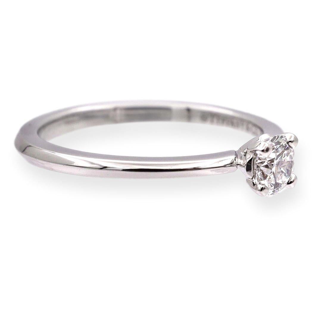 Tiffany & Co. engagement ring from the True collection finely crafted in 4 prongs with a basket setting showcasing the iconic T from the True collection featuring a round brilliant diamond center weighing 0.20 carats , E color , VS1 clarity .