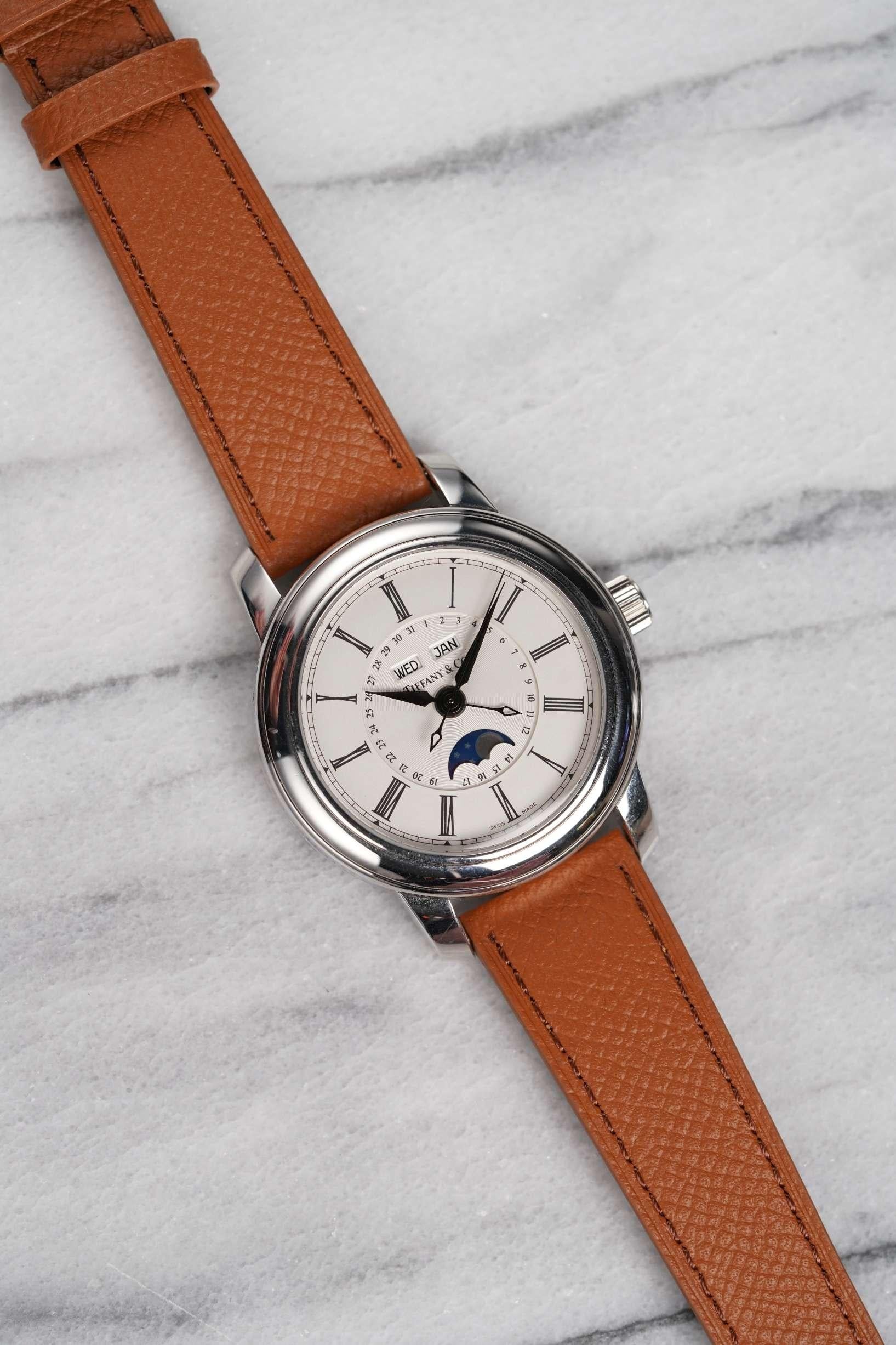 Aquí tienes un neo-vintage Tiffany & Co triple calendario fase lunar en platino automático de la década de 2000. Mantiene la hora y es totalmente funcional. Movimiento ETA. Las medidas incluyen un tamaño de la caja de 39 mm y una anchura de las asas