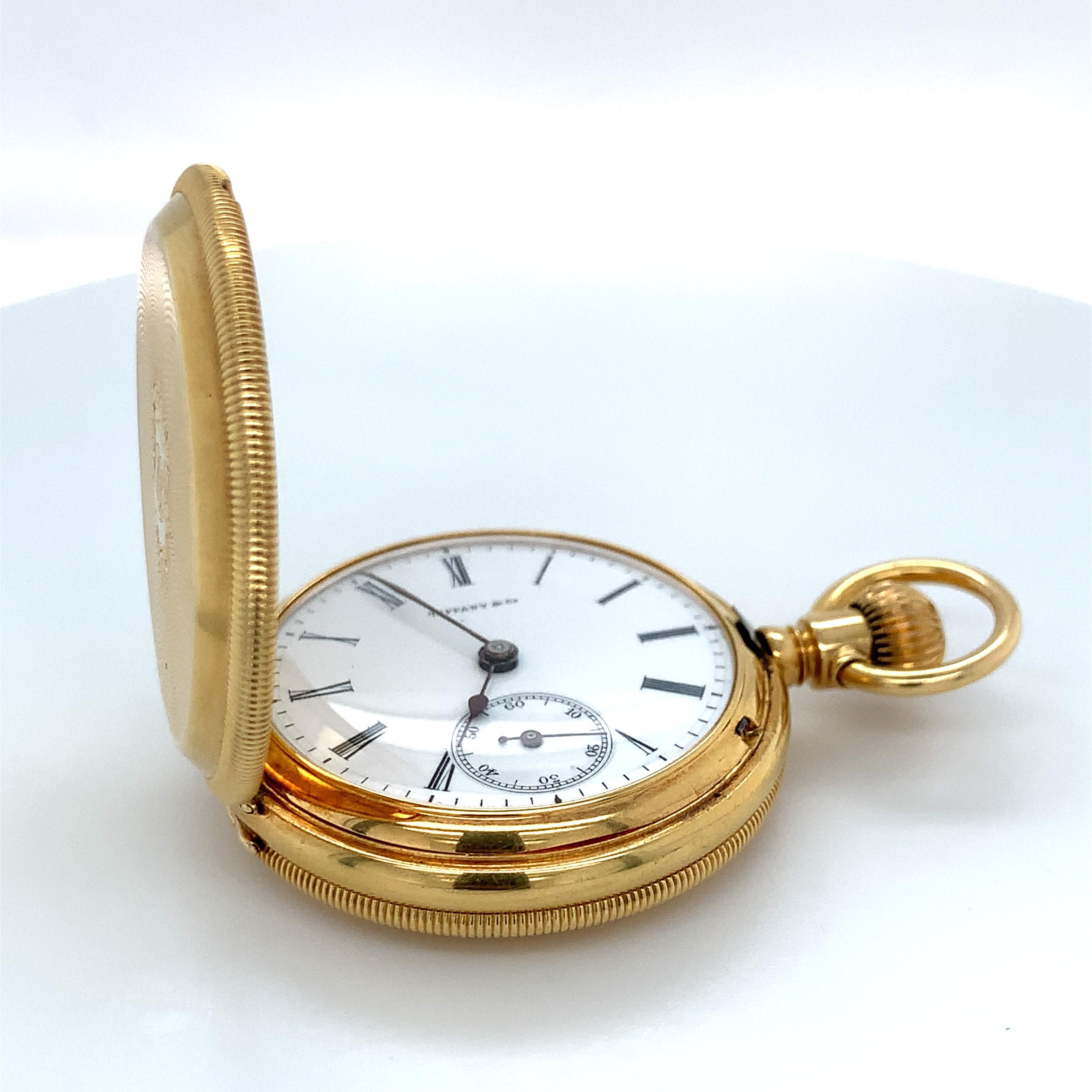 Un orologio da tasca di Tiffany & Co. in oro giallo 18 carati. Questo orologio è inciso e monogrammato. Il quadrante bianco è caratterizzato da numeri romani e da un quadrante secondario per i secondi a ore 6. Il movimento è a carica manuale,