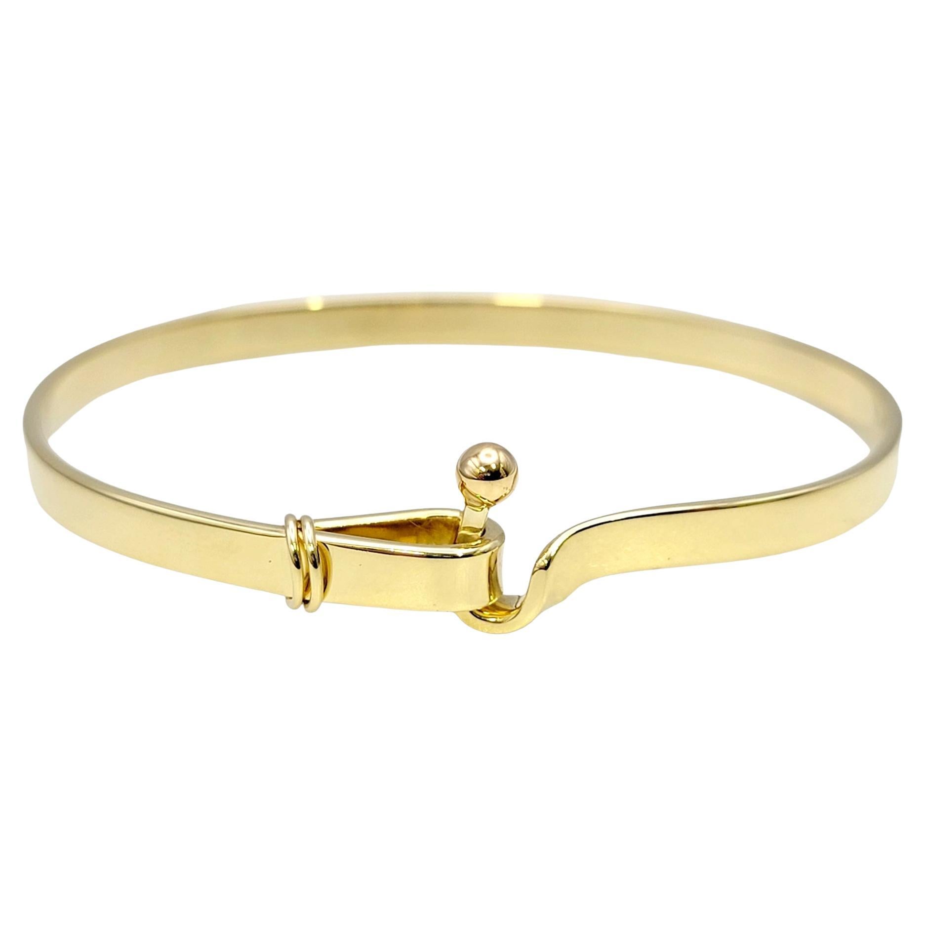 Contemporary elegance is at its finest with this sleek and stunning Tiffany & Co. hook and eye bangle bracelet. Founded in 1837 in New York City, Tiffany & Co. is one of the world's most storied luxury design houses recognized globally for its