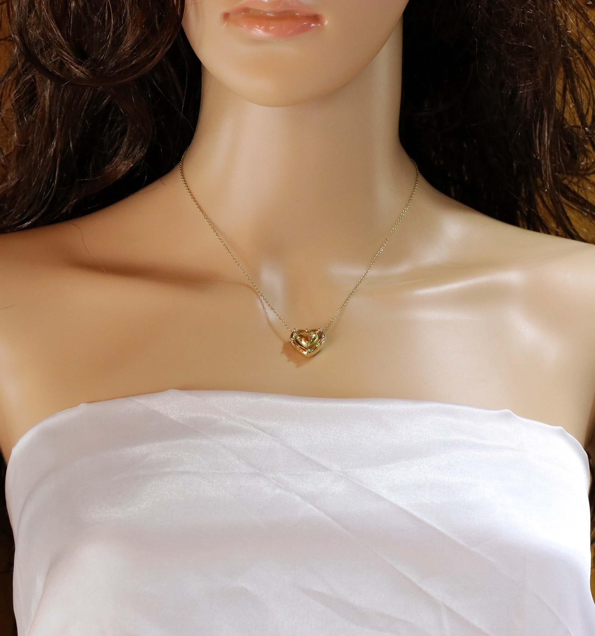 A ladies 18 karat yellow gold puffed heart pendant featuring a beaded edge suspended on a 15 inch 18K gold, cable link chain. The heart measures 5/8