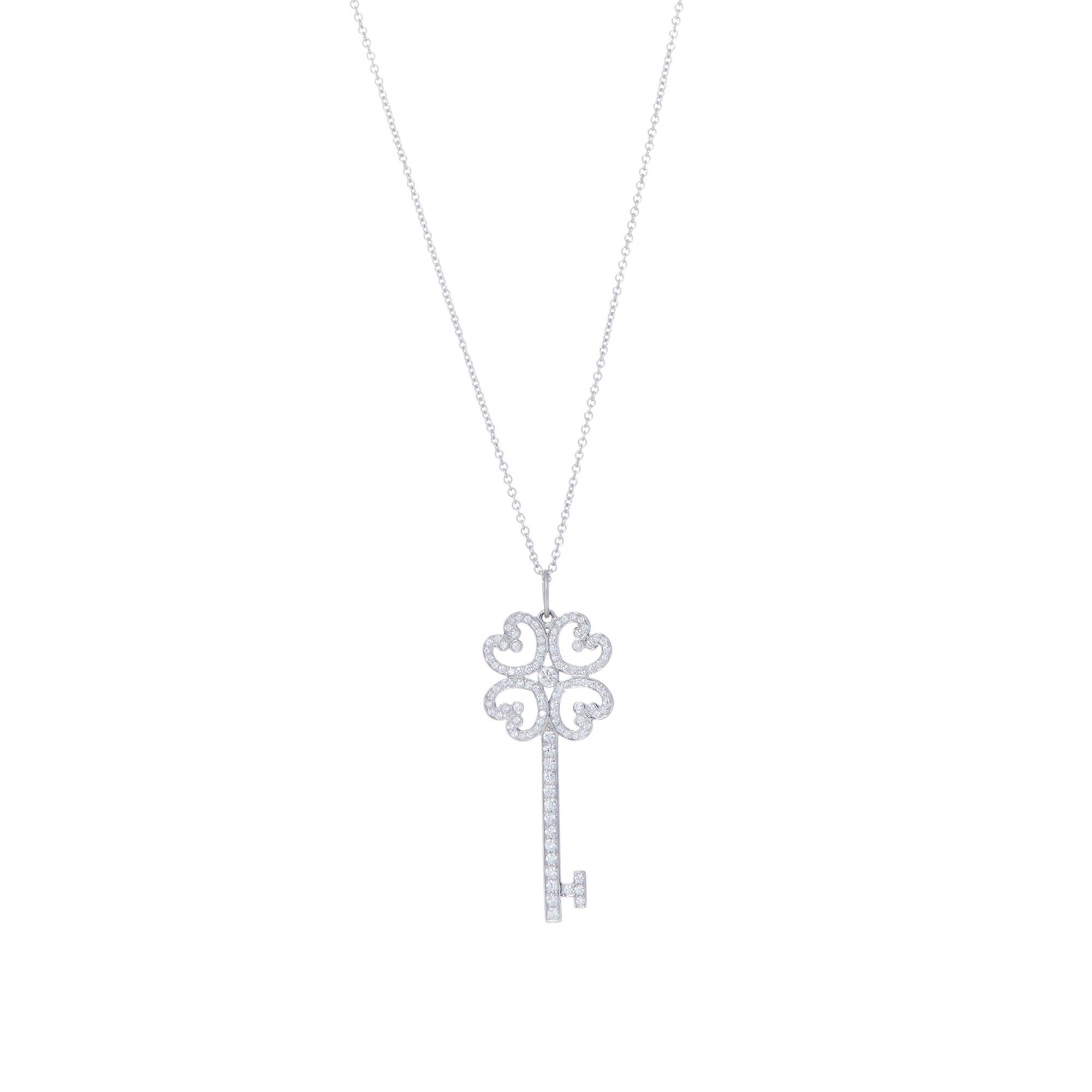 Authentic Tiffany & Co. Quatra Heart pendant from the Tiffany Keys collection. Crafted in platinum, the top of the key is composed of four pave set hearts surrounding a bezel set round brilliant cut diamond. The length of the key is also pave set