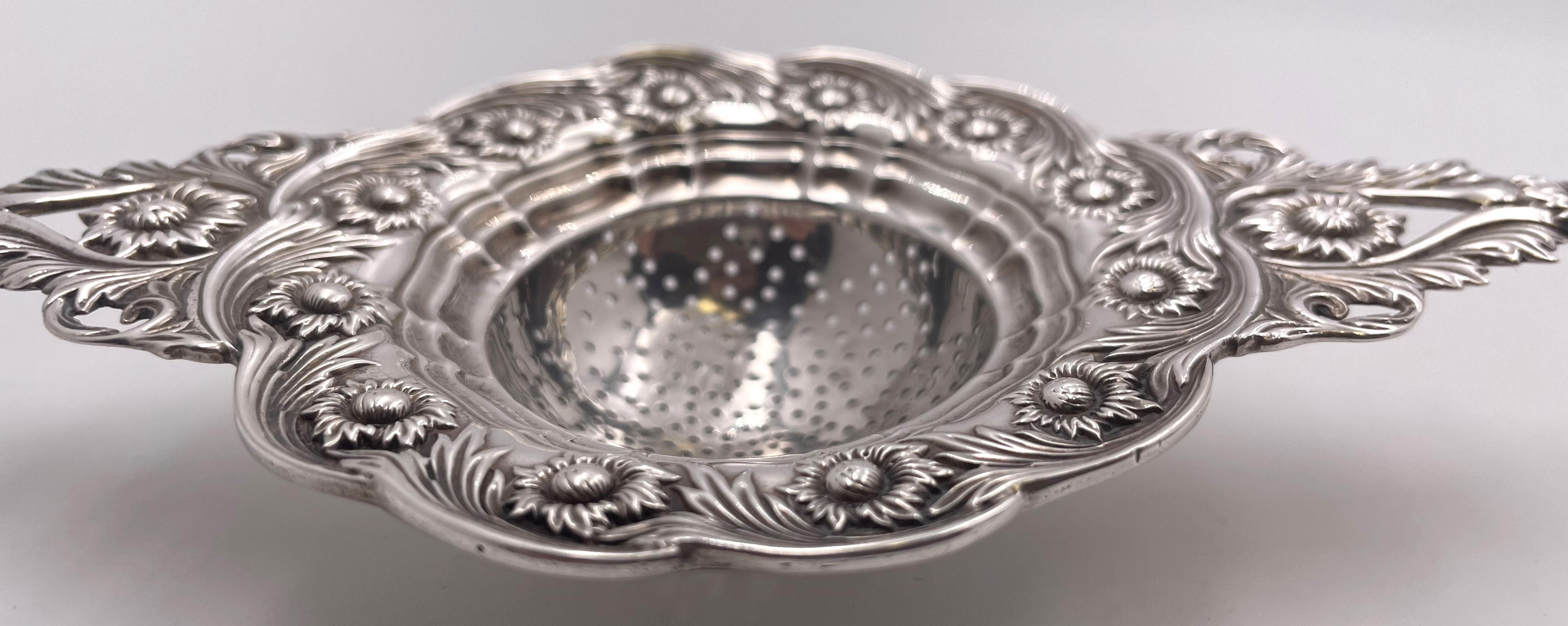 Tiffany & Co. extremely rare sterling silver tea strainer in the celebrated Chrysanthemum pattern, with two handles, adorned with chrysanthemum floral motifs. It measures 6 1/2'' from handle to handle by 3 1/2''in depth by 3/4'' in height and bears