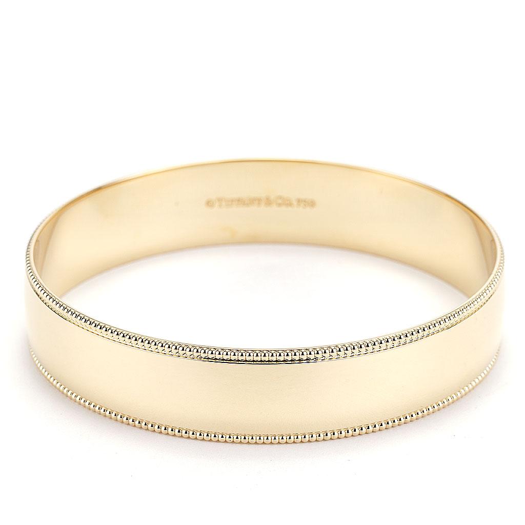 Previously owned retired Tiffany & Co. 14 mm solid bangle with beaded/ milgrain edges. The bangle is made of 18K yellow gold and weighs 39.00 DWT (approx. 60.65 grams).