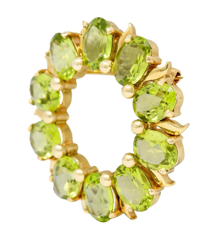 Circular brooch comprised of oval peridot cabochon

Ten cabochons measuring approximately 8mm x 6mm

Evenly matched bright yellowish-green and highly saturated in color

Prong and bead set with alternating stylized leaf motif

Completed by a pin