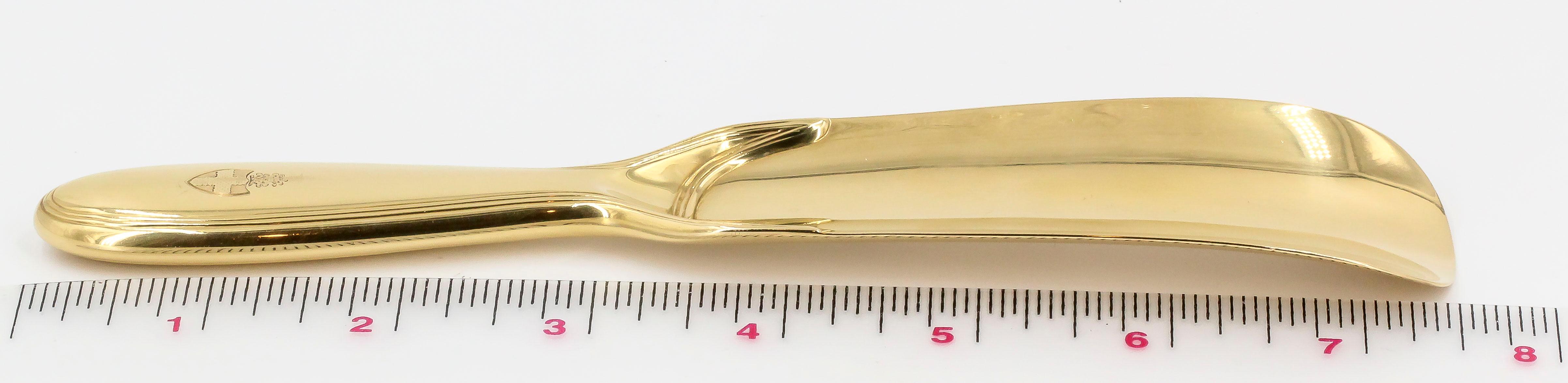 Chic and unusual 18K yellow gold shoehorn by Tiffany & Co. It features a crest at the bottom of the handle bearing a cross. Beautifully made and highly functional.

Hallmarks: Tiffany & Co. Makers, 18KT Gold, reference numbers, maker's mark.