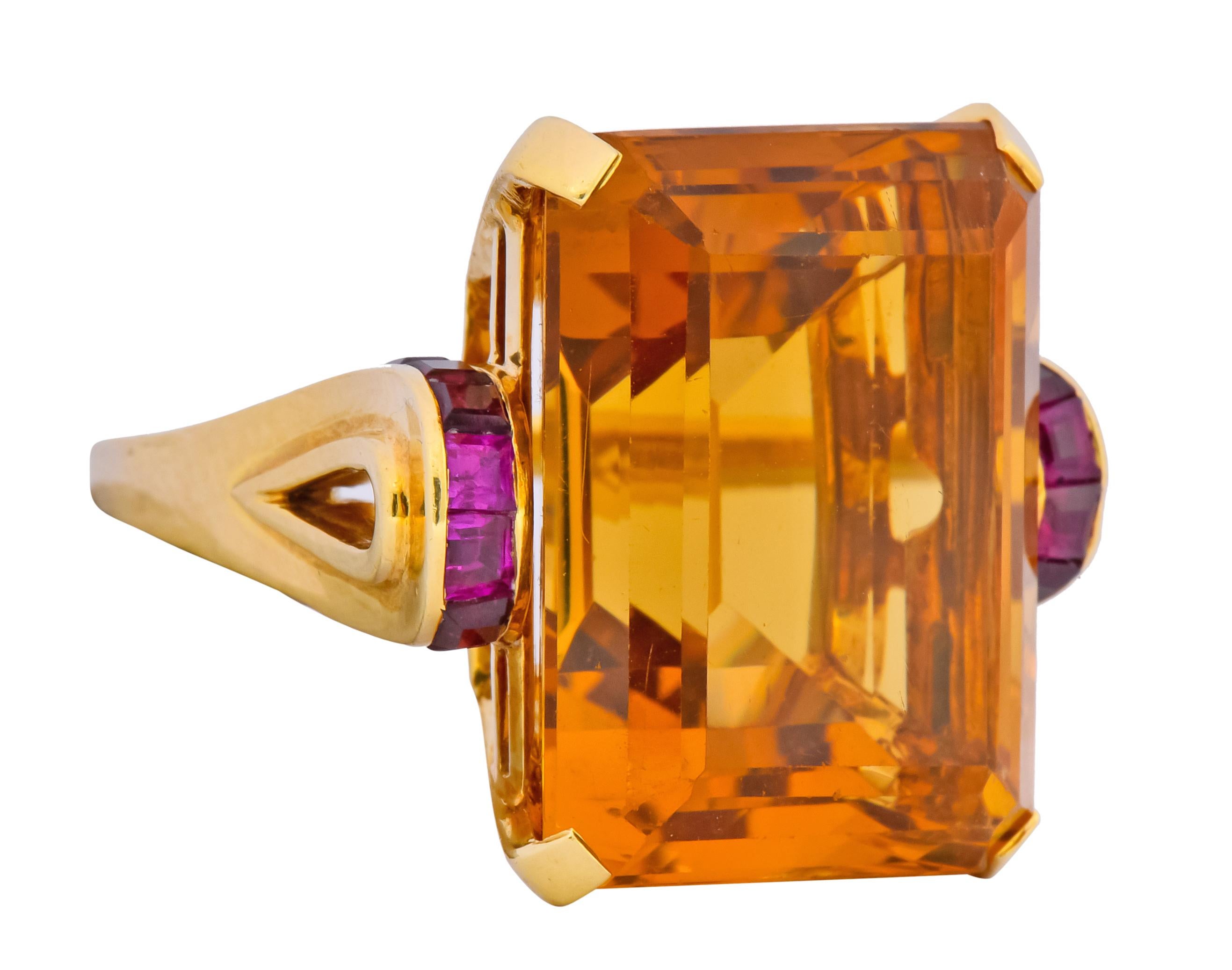 Centering a basket set rectangular step cut citrine weighing approximately 23.90 carats, transparent and a medium-dark orangey-yellow 

Flanked by channel set calibré cut rubies weighing approximately 0.64 carat total, very well matched and a