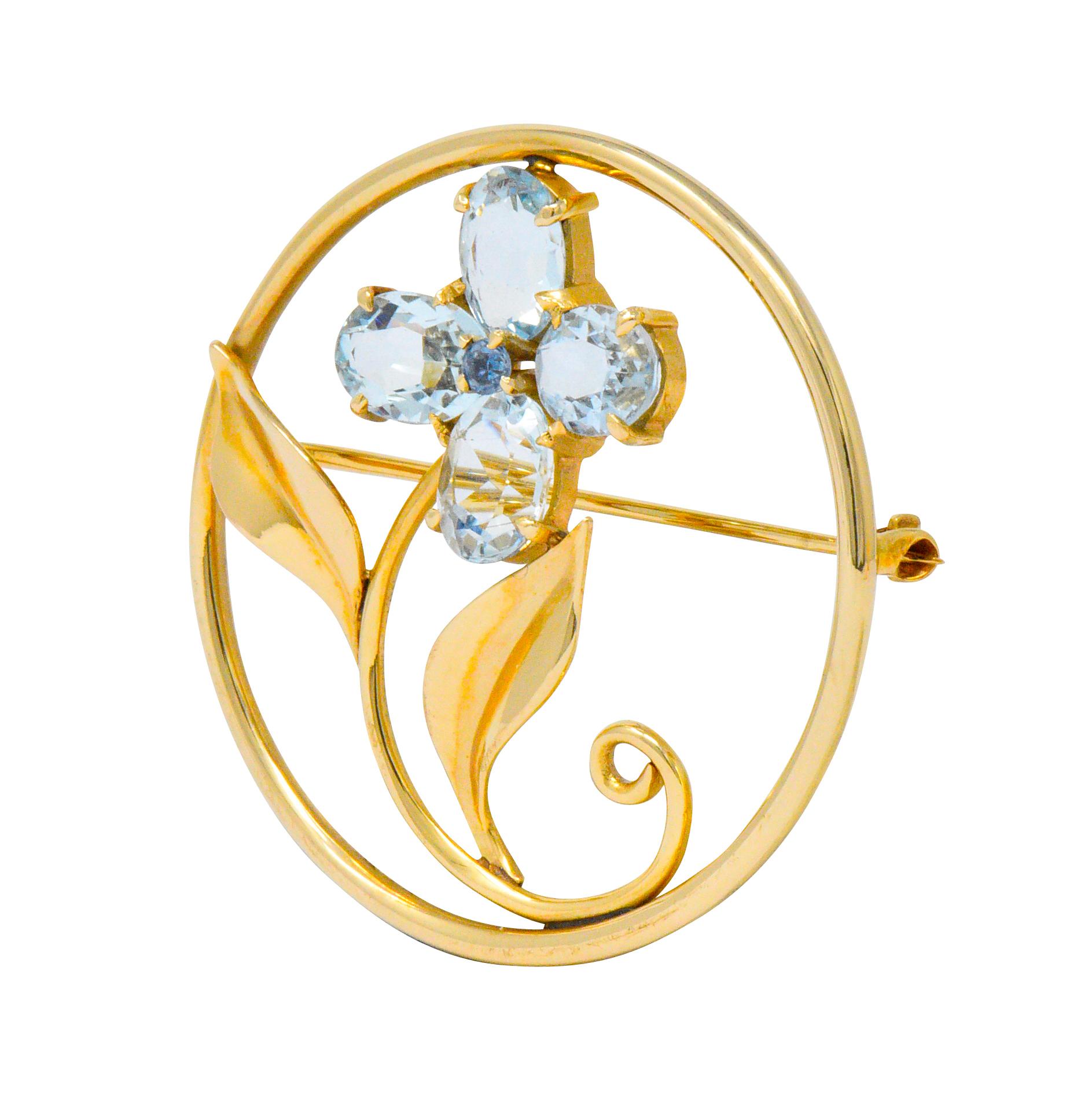 Designed as a circle style brooch centering a flower

Four oval cut aquamarine petals, weighing approximately 5.00 carats total, bright light blue and very well matched

Centering a round cut sapphire weighing approximately 0.15 carat, bright